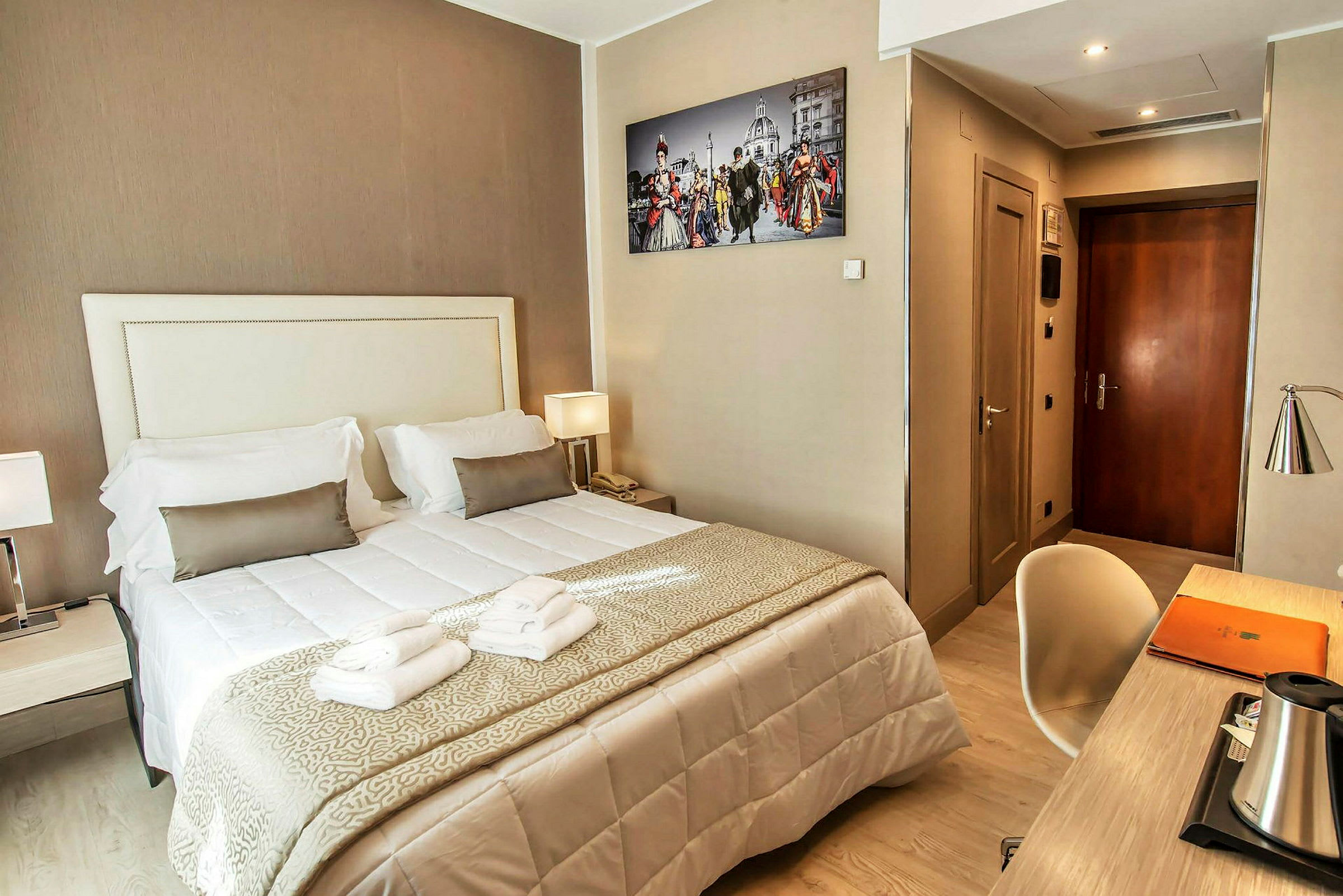 Hotellrum med dubbelsäng, skrivbord, och väggfotografi. (AI-genererad text)