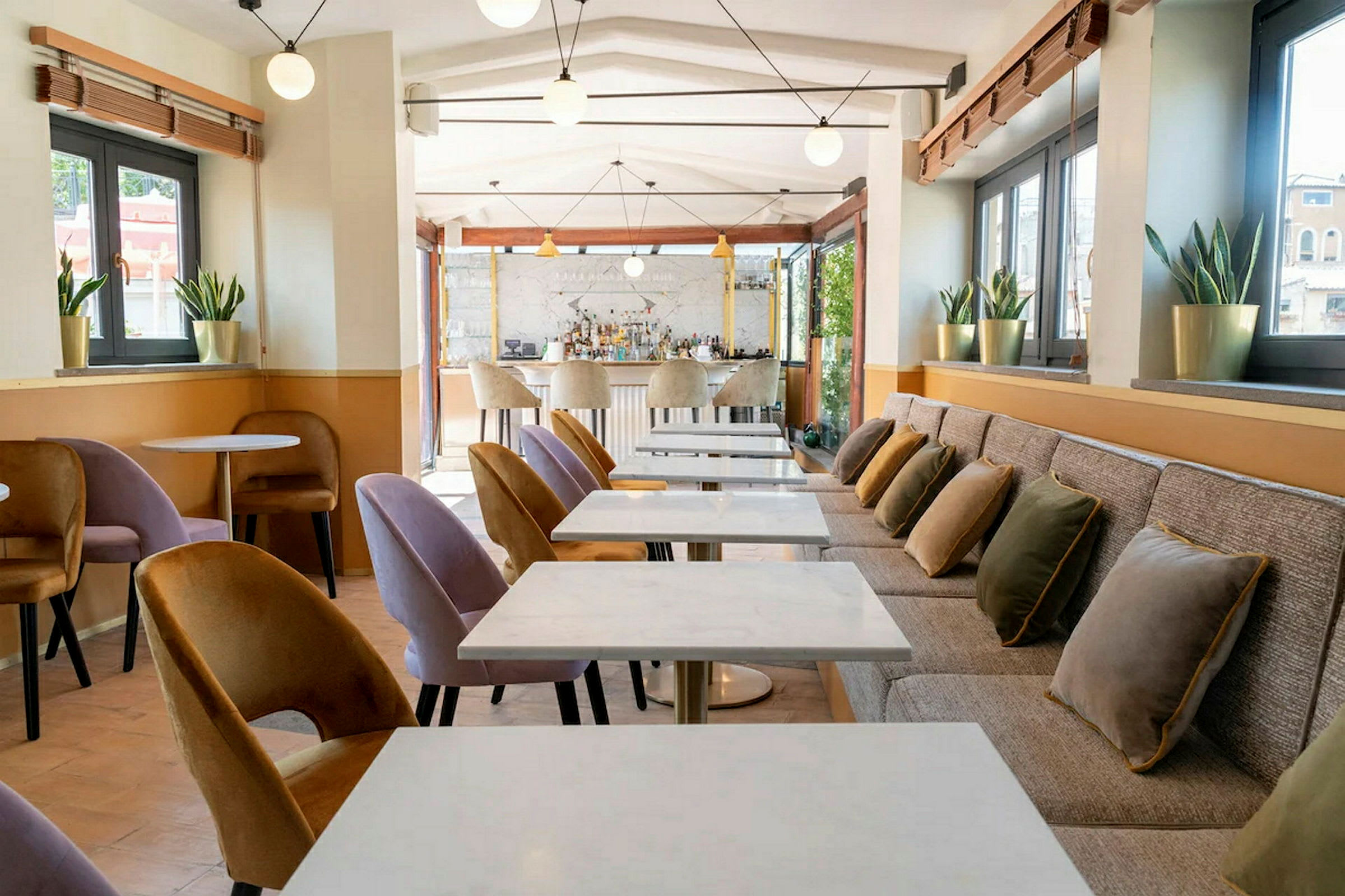 Ett modernt café med marmorbord, stoppade stolar och kuddar på en lång bänk. (AI-genererad text)