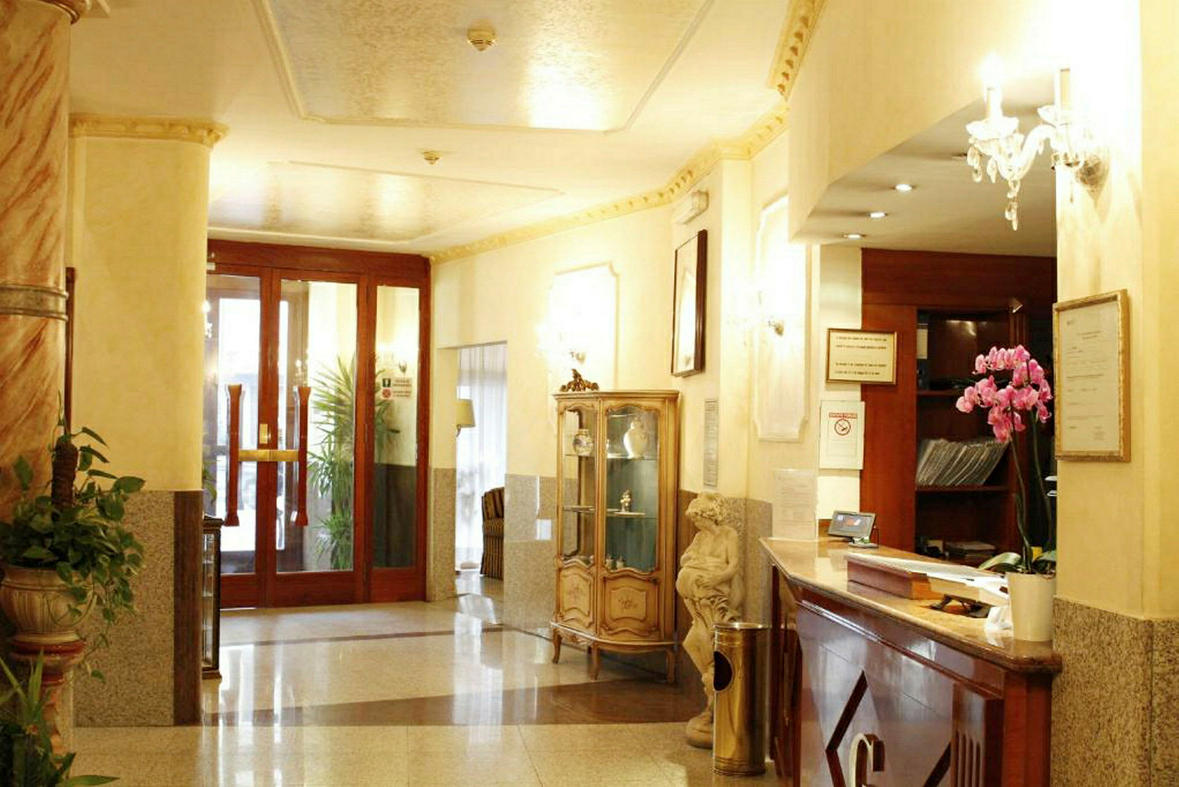 Interiör av en hotellobby med reception, glasskåp, växter och ornament. (AI-genererad text)