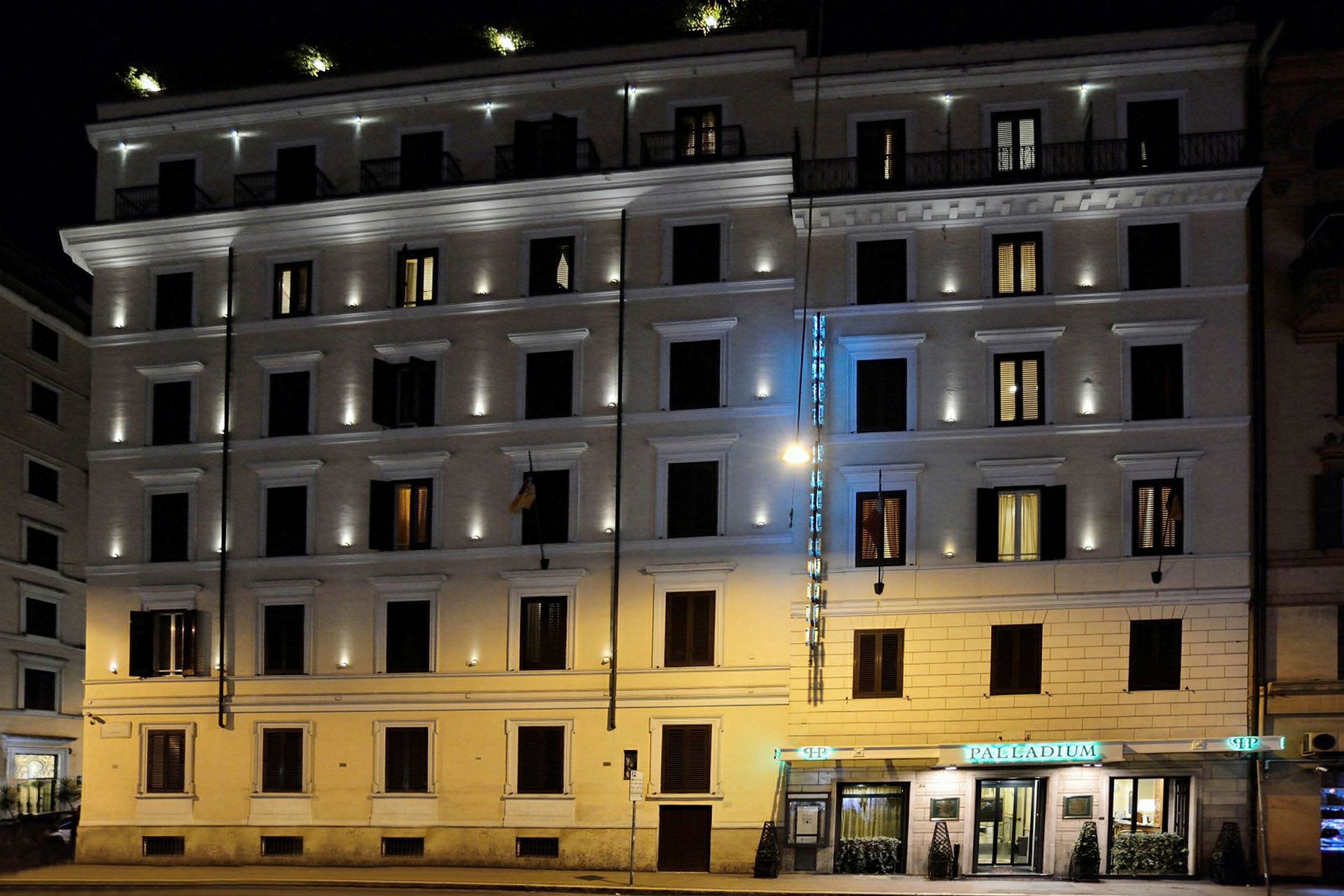 Ett kvällsbelyst flerbostadshus med en hotellskylt och upplysta fönster. (AI-genererad text)