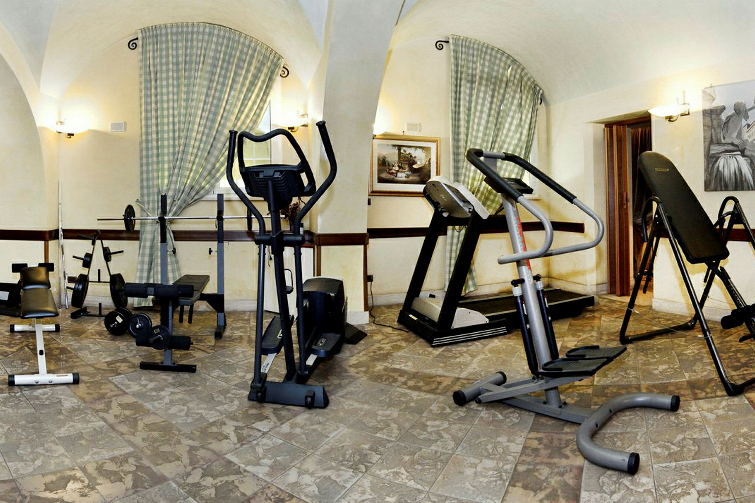 Ett rum inrett som gym med träningsutrustning som motionscyklar, löpband och styrkemaskiner. (AI-genererad text)