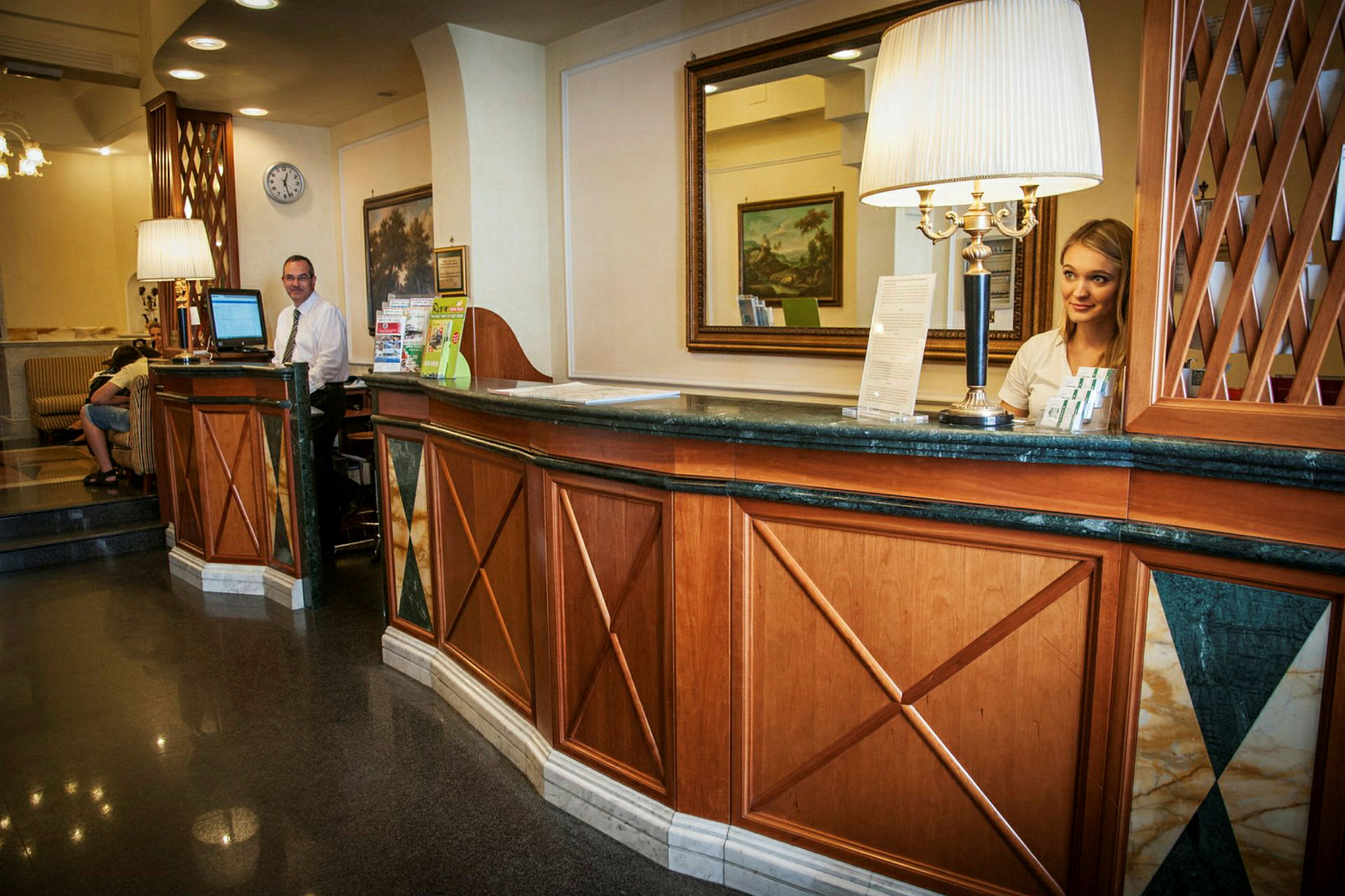 Receptionen i ett hotell med träpaneler, en spegel på väggen, och informationsmaterial på disken. (AI-genererad text)