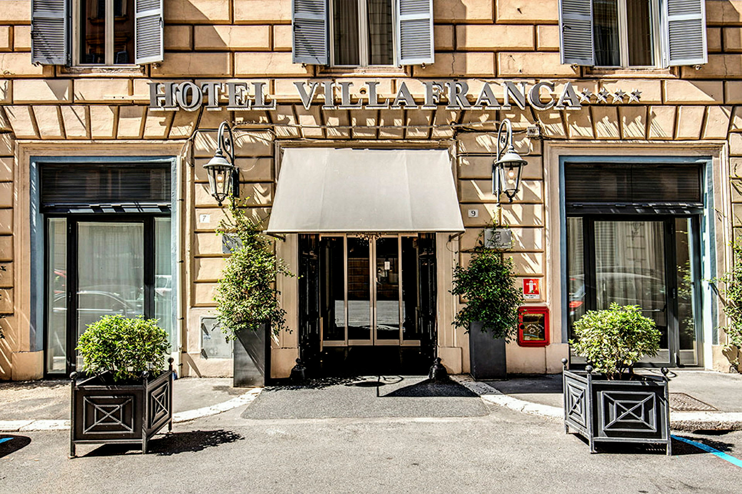 Hotellentré med skylt, fönster och växter i krukor. (AI-genererad text)