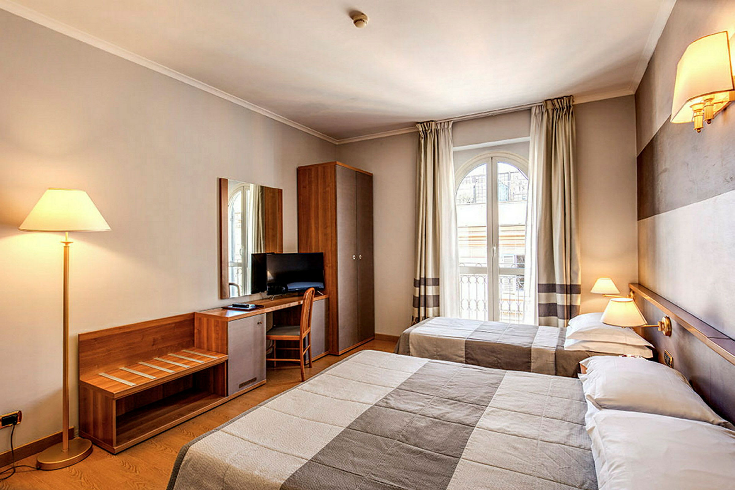 Hotellrum med två sängar, skrivbord med stol, tv och stilfull inredning. (AI-genererad text)