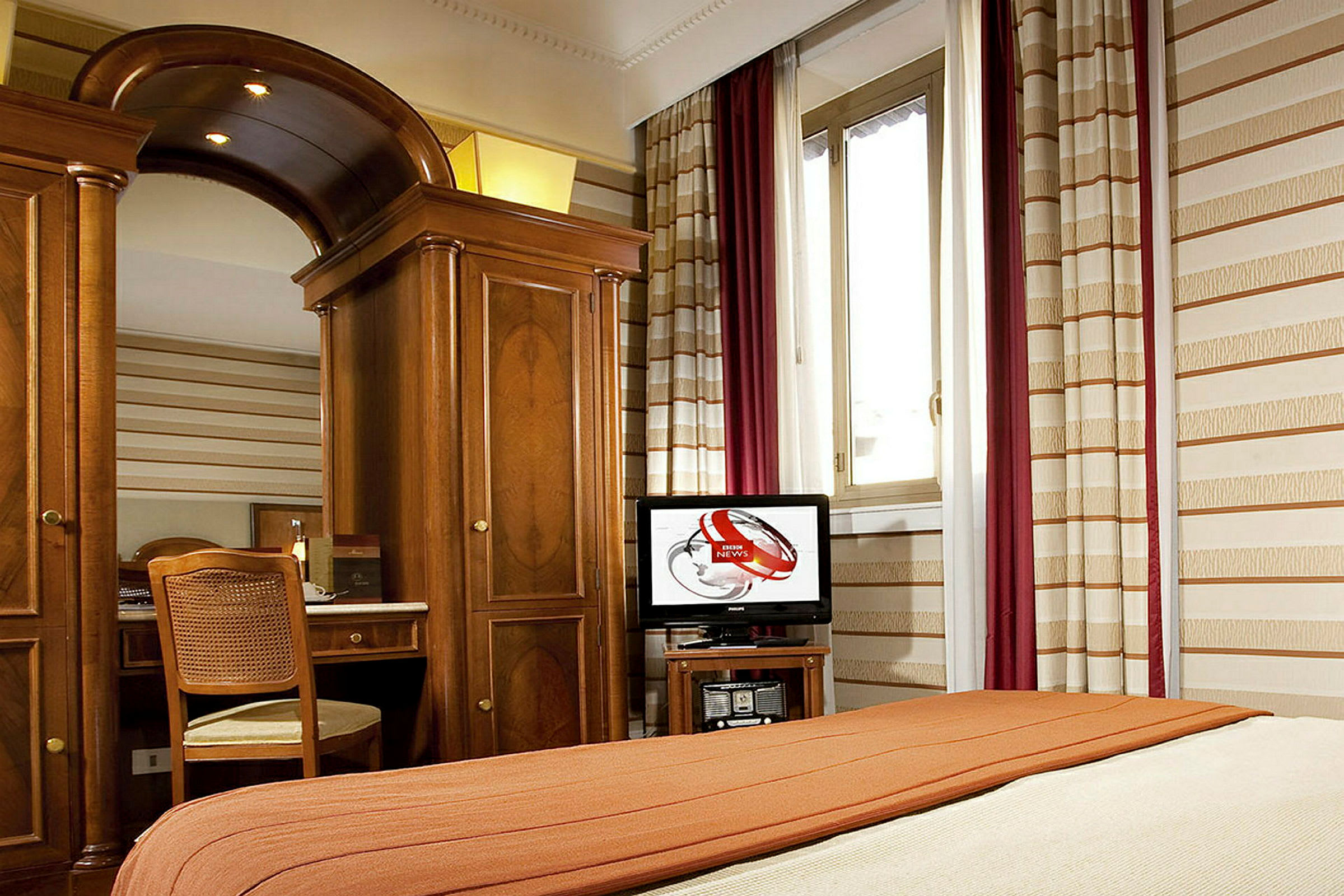 Ett hotellrum med en säng, träinredning, spegel, stol och ett fönster. (AI-genererad text)