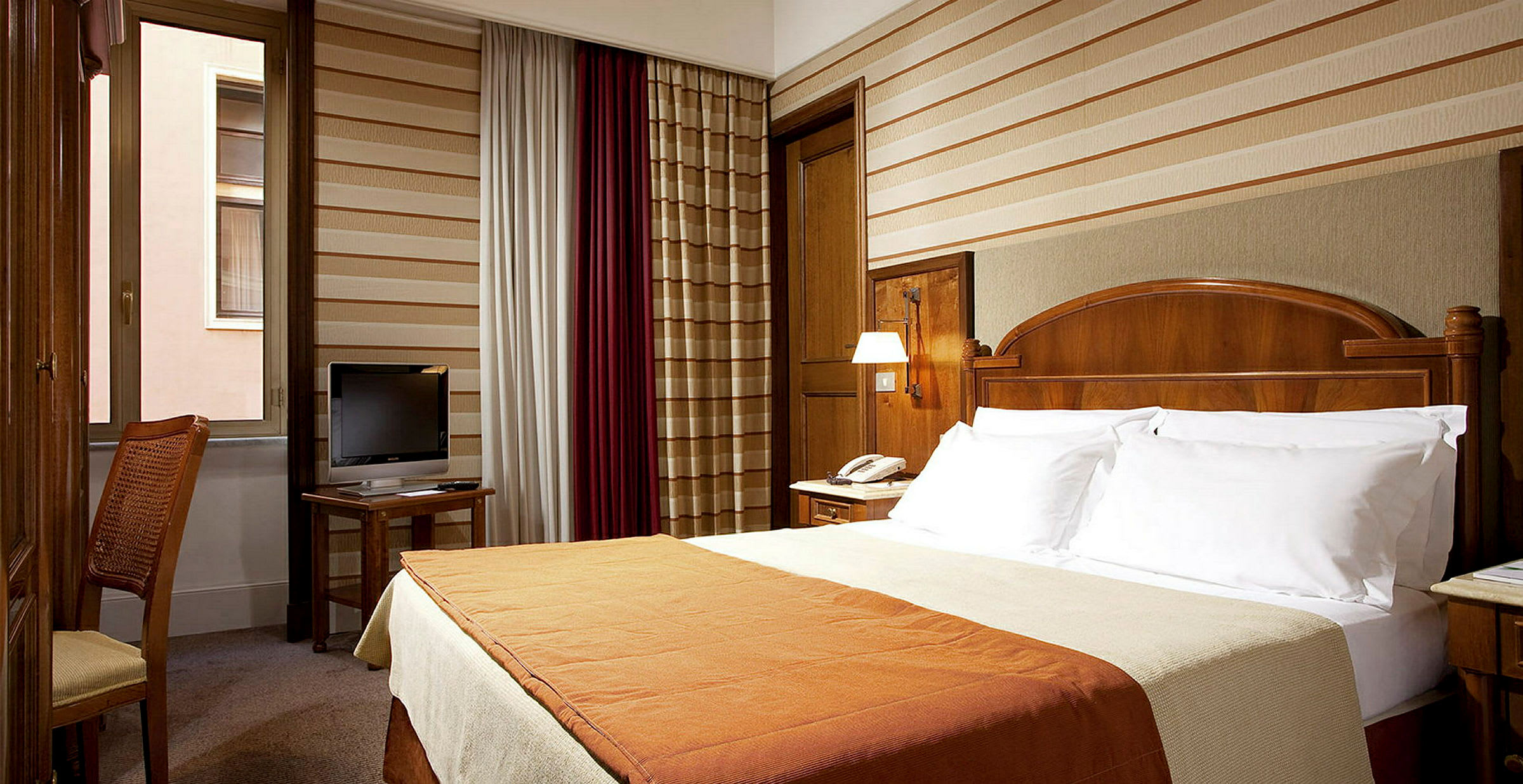 Ett hotellrum med en dubbelsäng, ett skrivbord med en TV och ett fönster. (AI-genererad text)