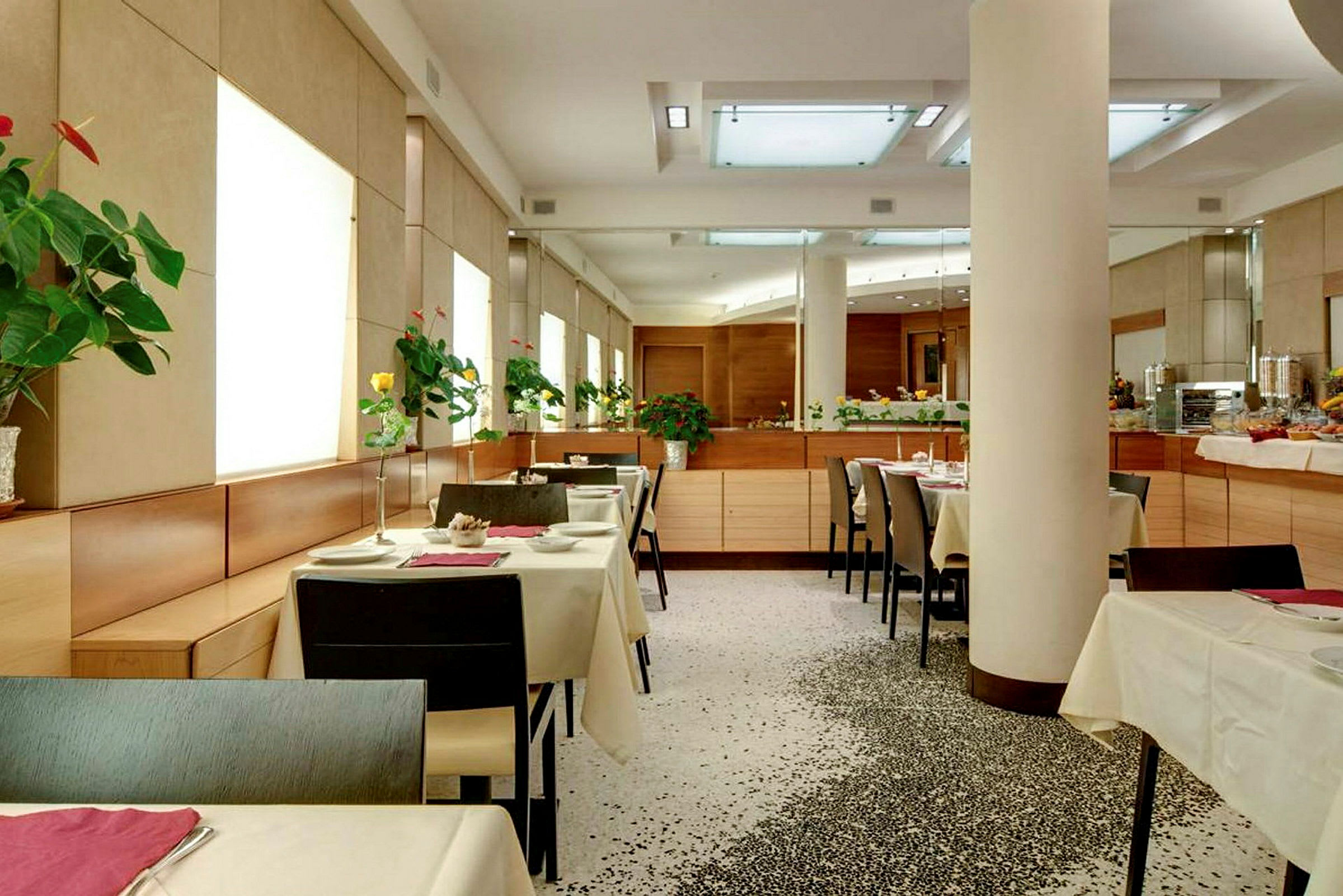 En modern restaurang med uppsatta bord och blommor på varje bord. (AI-genererad text)
