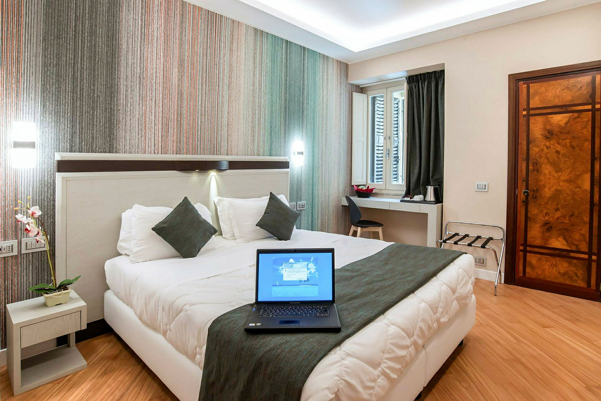 Ett hotellrum med en dubbelsäng, ett skrivbord och en laptop på sängen. (AI-genererad text)