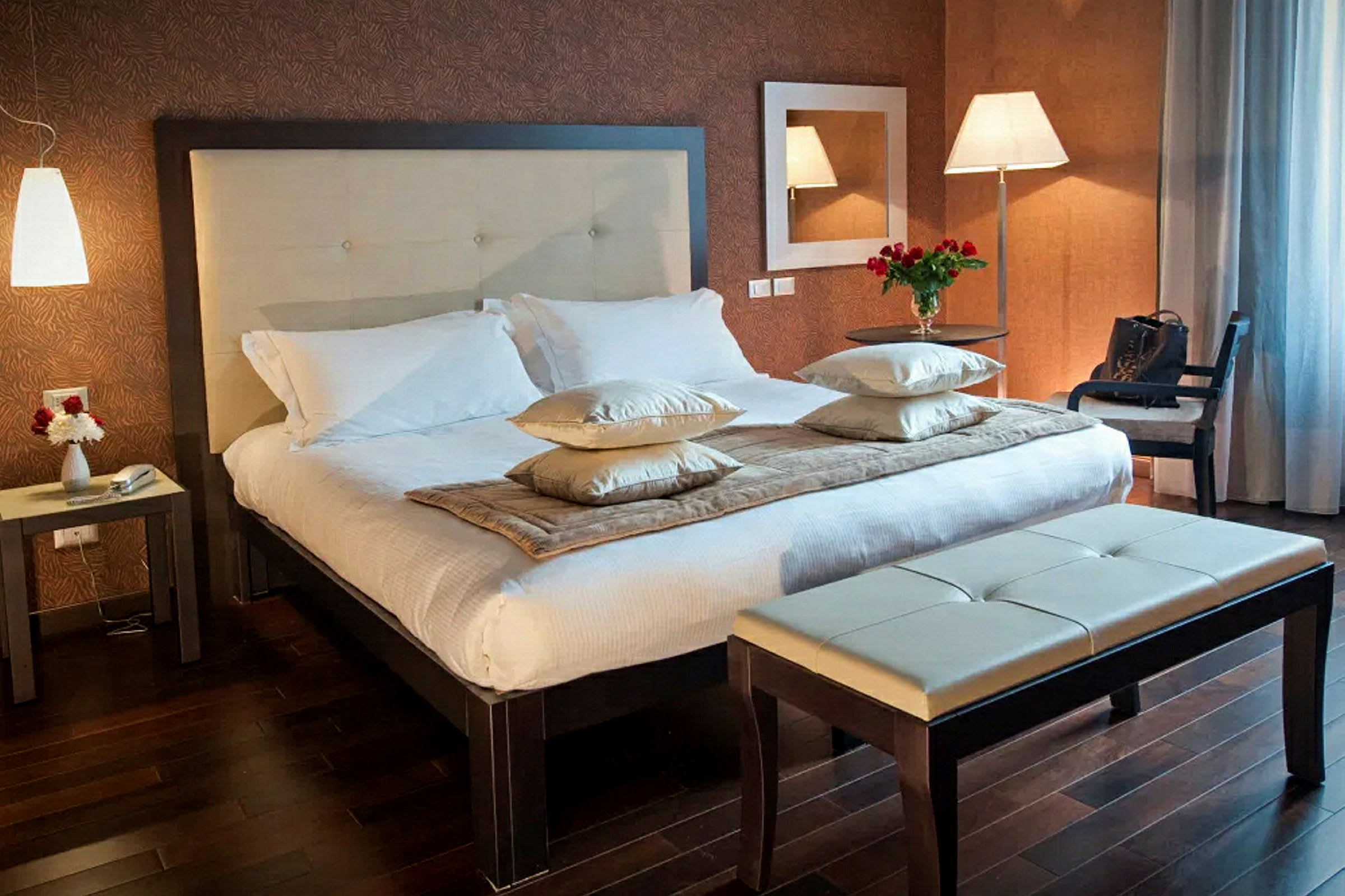 Ett hotellrum med en dubbelsäng, sidobord och bänk. (AI-genererad text)