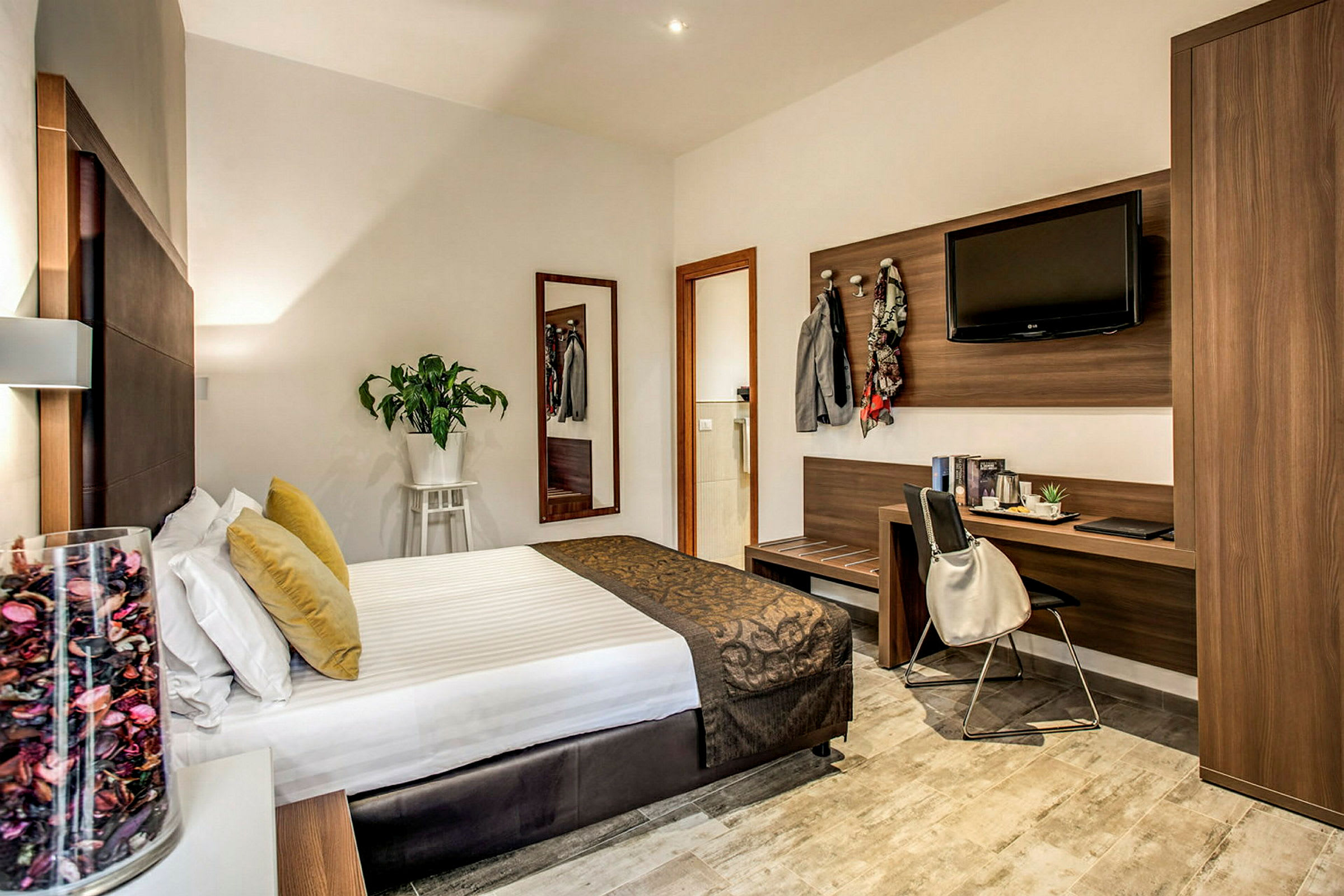 Ett hotellrum med en säng, ett skrivbord och en garderob, dekorerat med moderna möbler. (AI-genererad text)