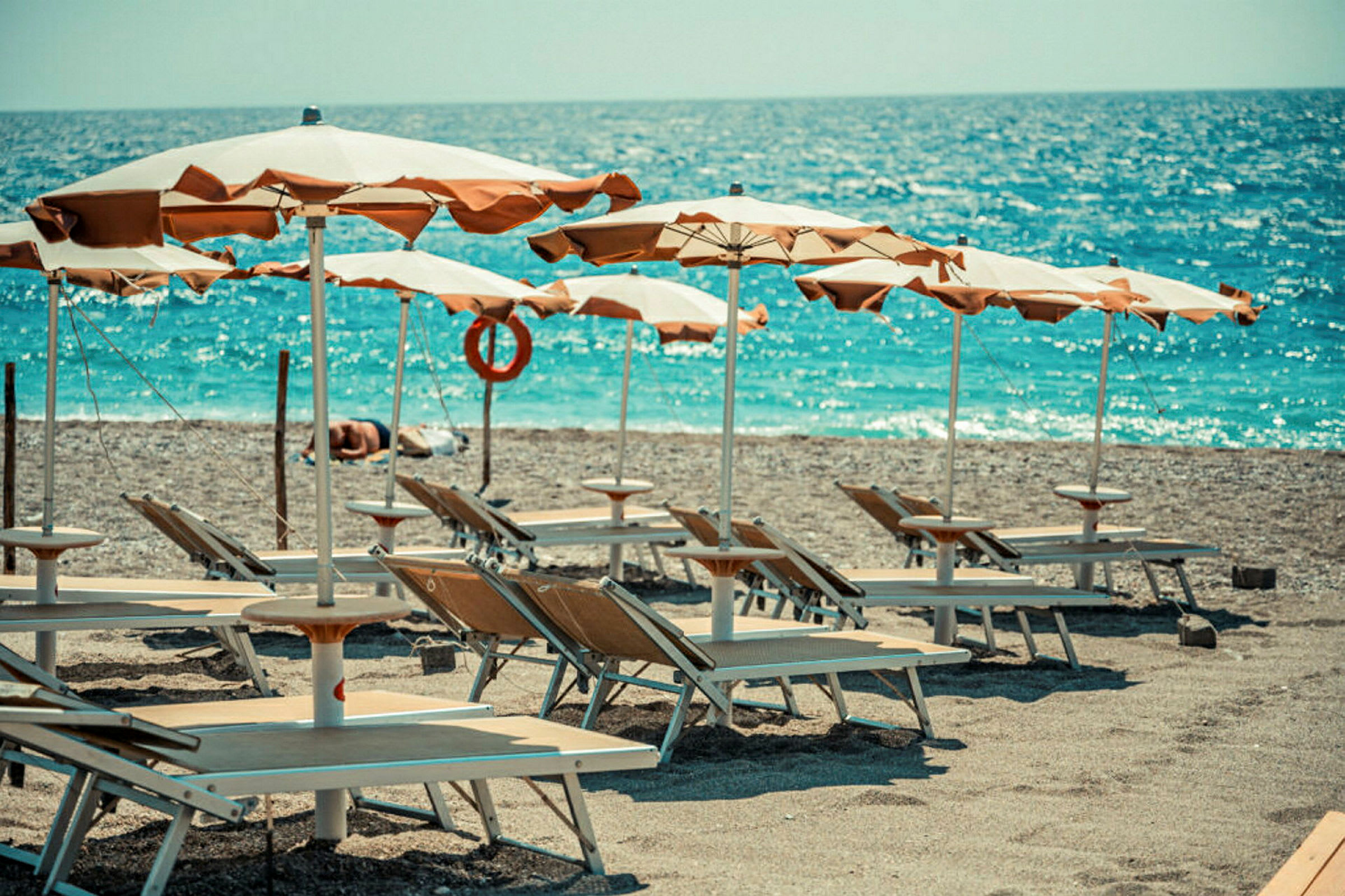 Solstolar och parasoller på en strand vid havet. (AI-genererad text)