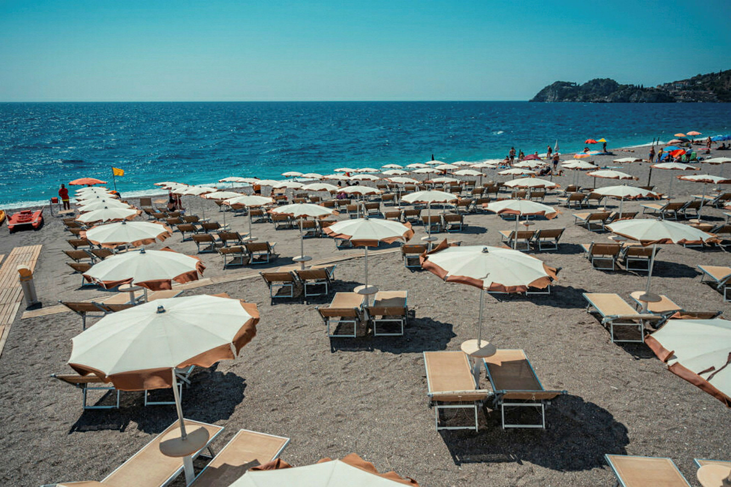 Strand med parasoller och solstolar vid havet. (AI-genererad text)