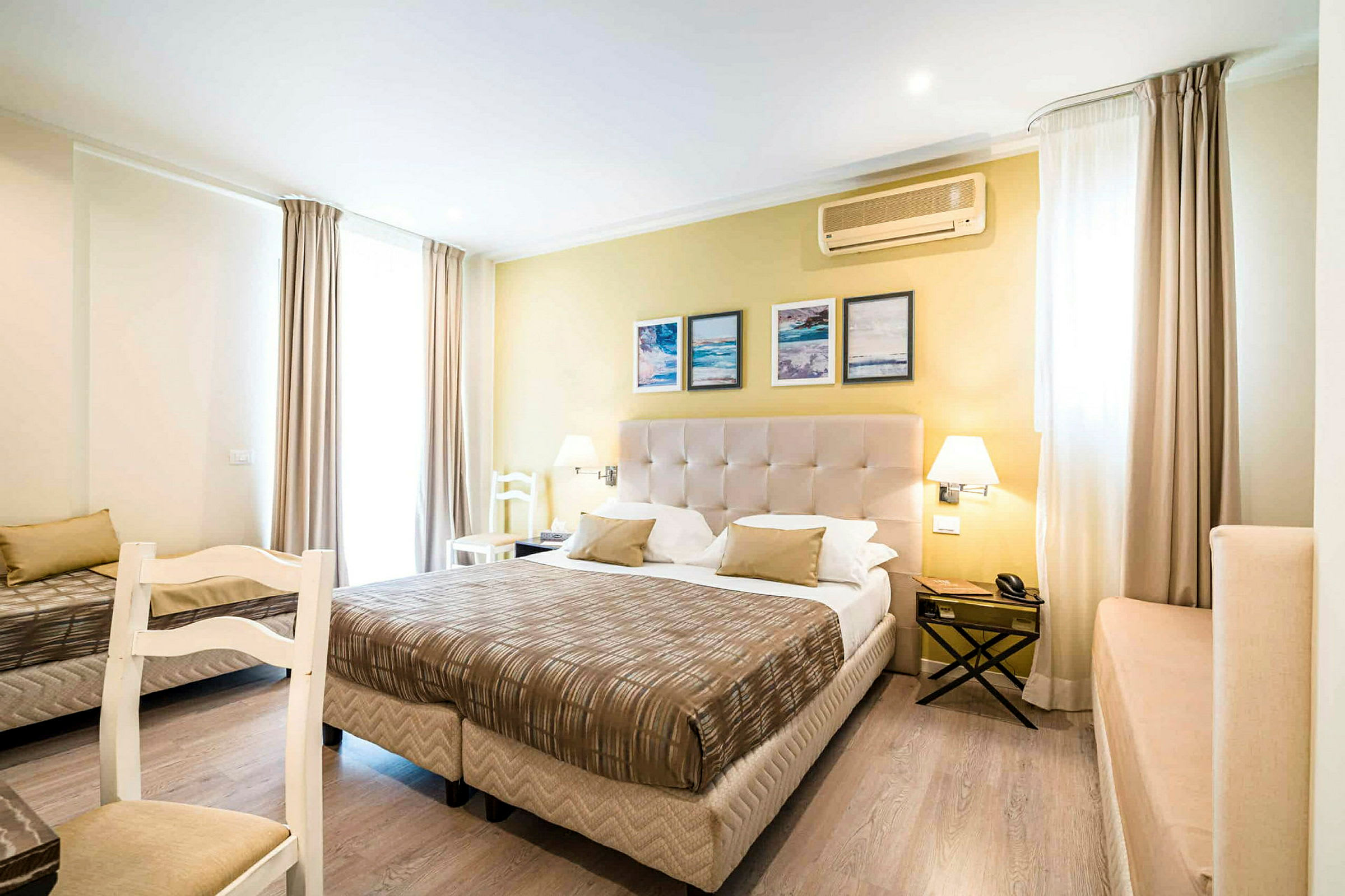 Ett välmöblerat hotellrum med en säng, en stol och ljus inredning. (AI-genererad text)