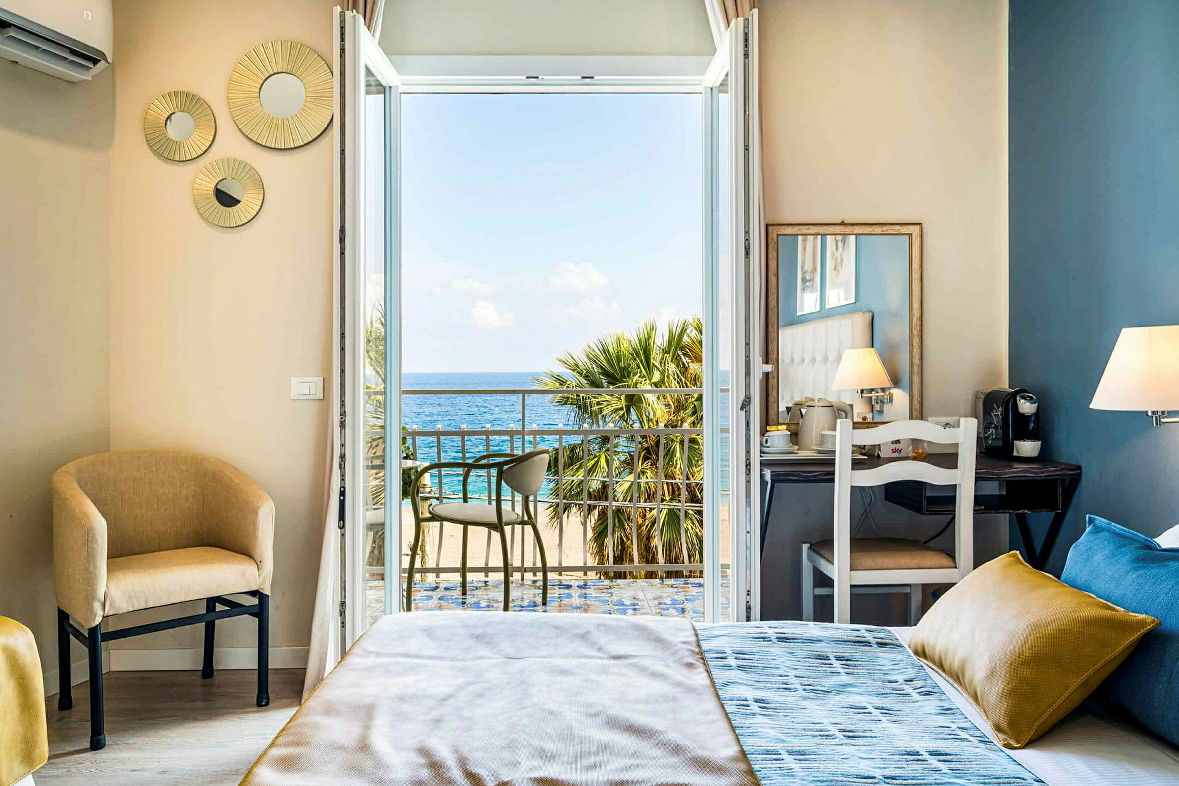 Ett hotellrum med säng och utsikt mot havet genom öppna balkongdörrar. (AI-genererad text)