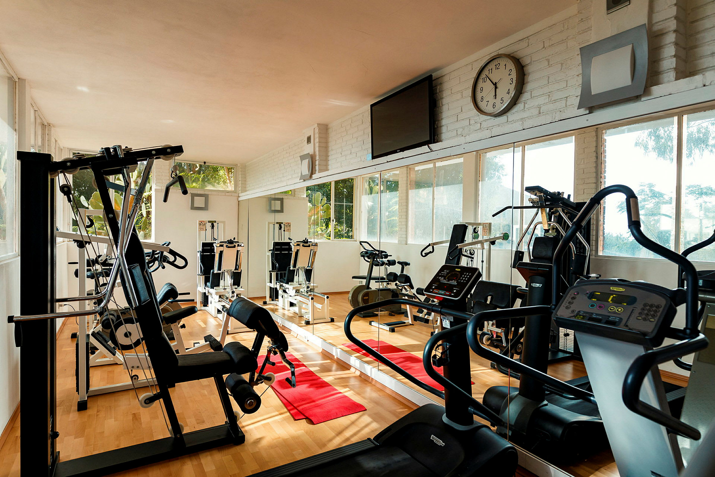 Ett gym med träningsmaskiner, löpband och spegelväggar. (AI-genererad text)