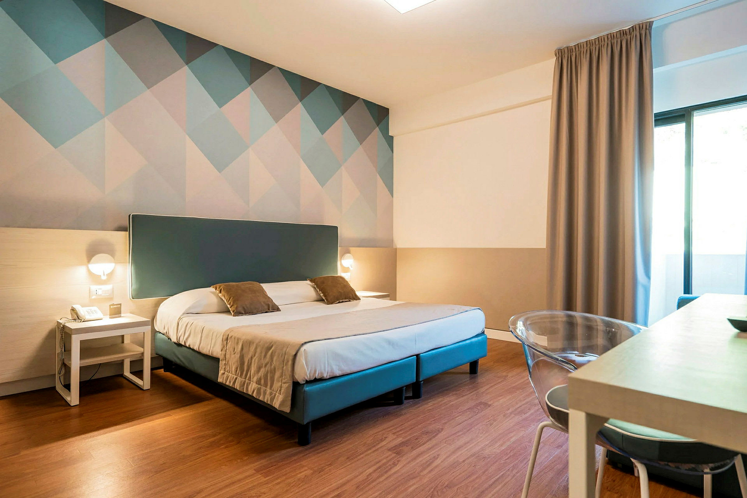 Ett hotellrum med en dubbelsäng, två sängbord och en dekorativ vägg bakom sängen. (AI-genererad text)
