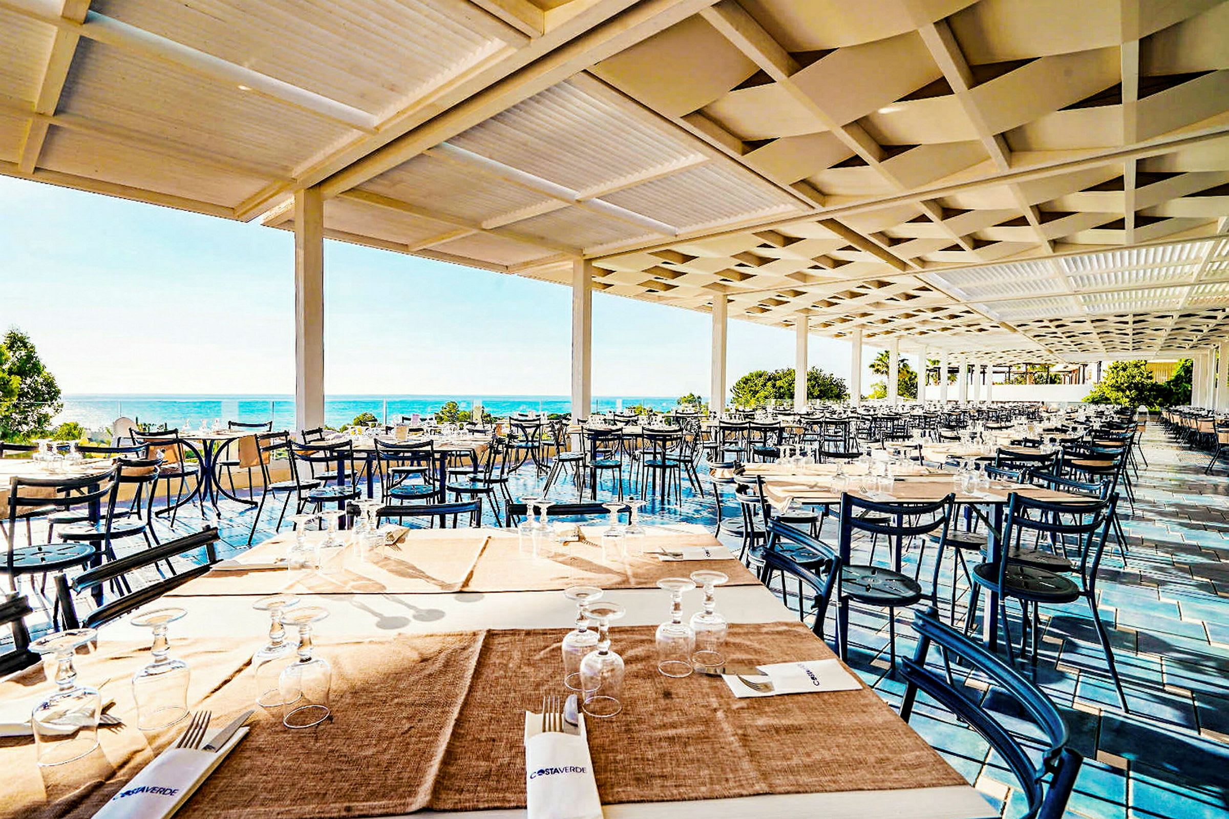 Restaurang med havsutsikt, bord dukade med servetter och glas. (AI-genererad text)