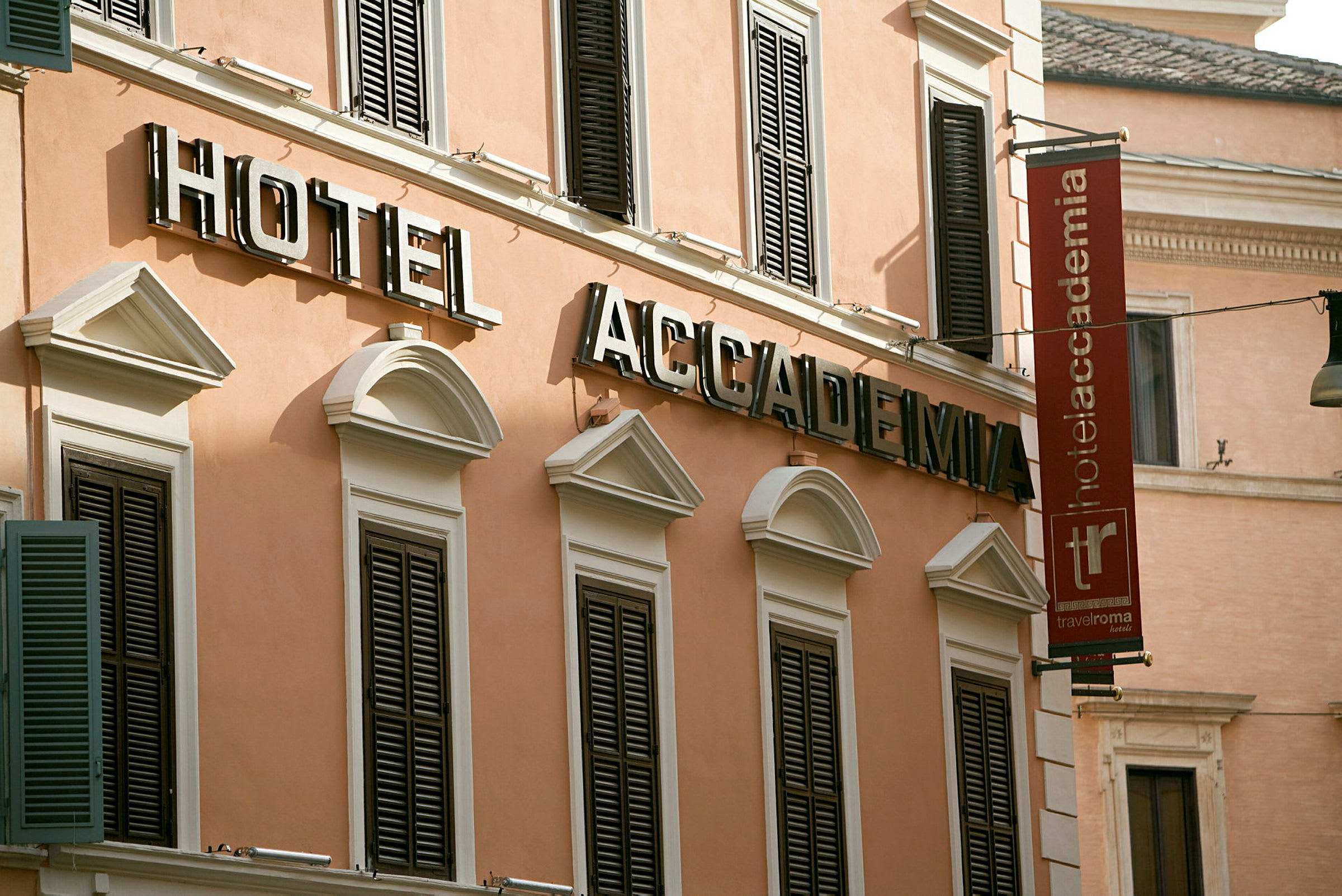Fasad av hotellbyggnad med skyltar som säger "Hotel Accademia" i stora bokstäver. (AI-genererad text)