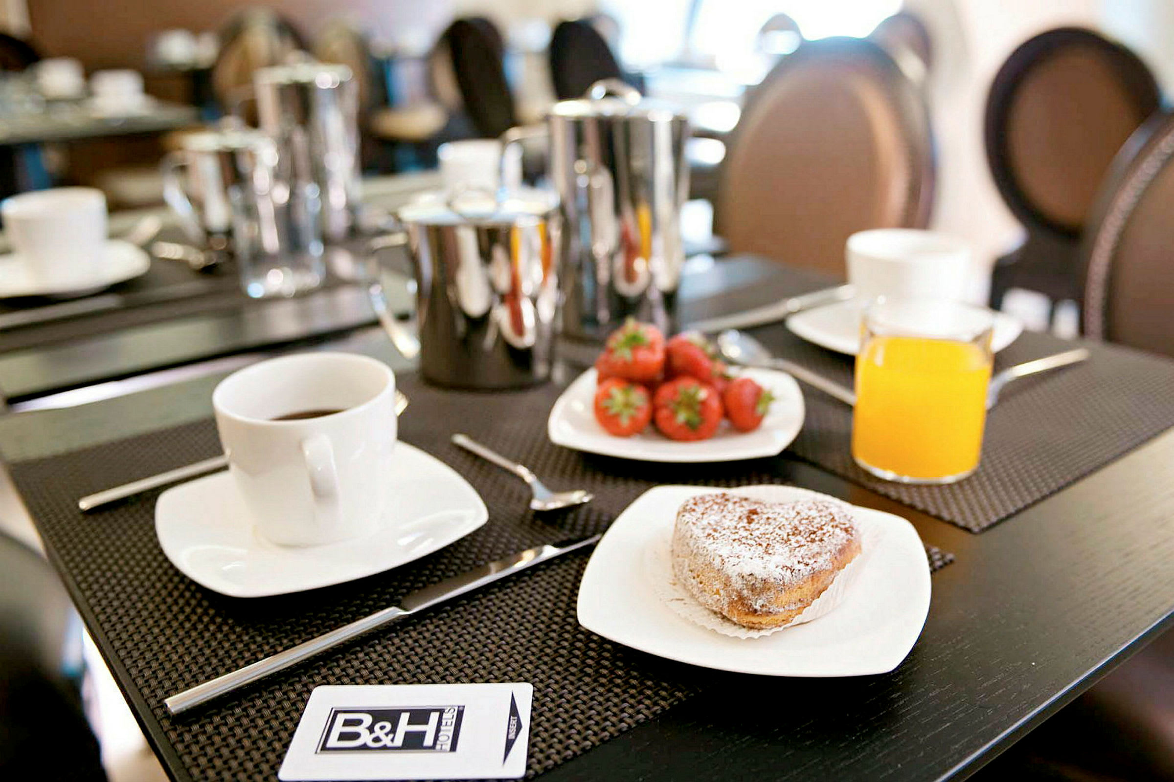 Frukostbord med kaffe, bakverk, färska jordgubbar och ett glas apelsinjuice. (AI-genererad text)