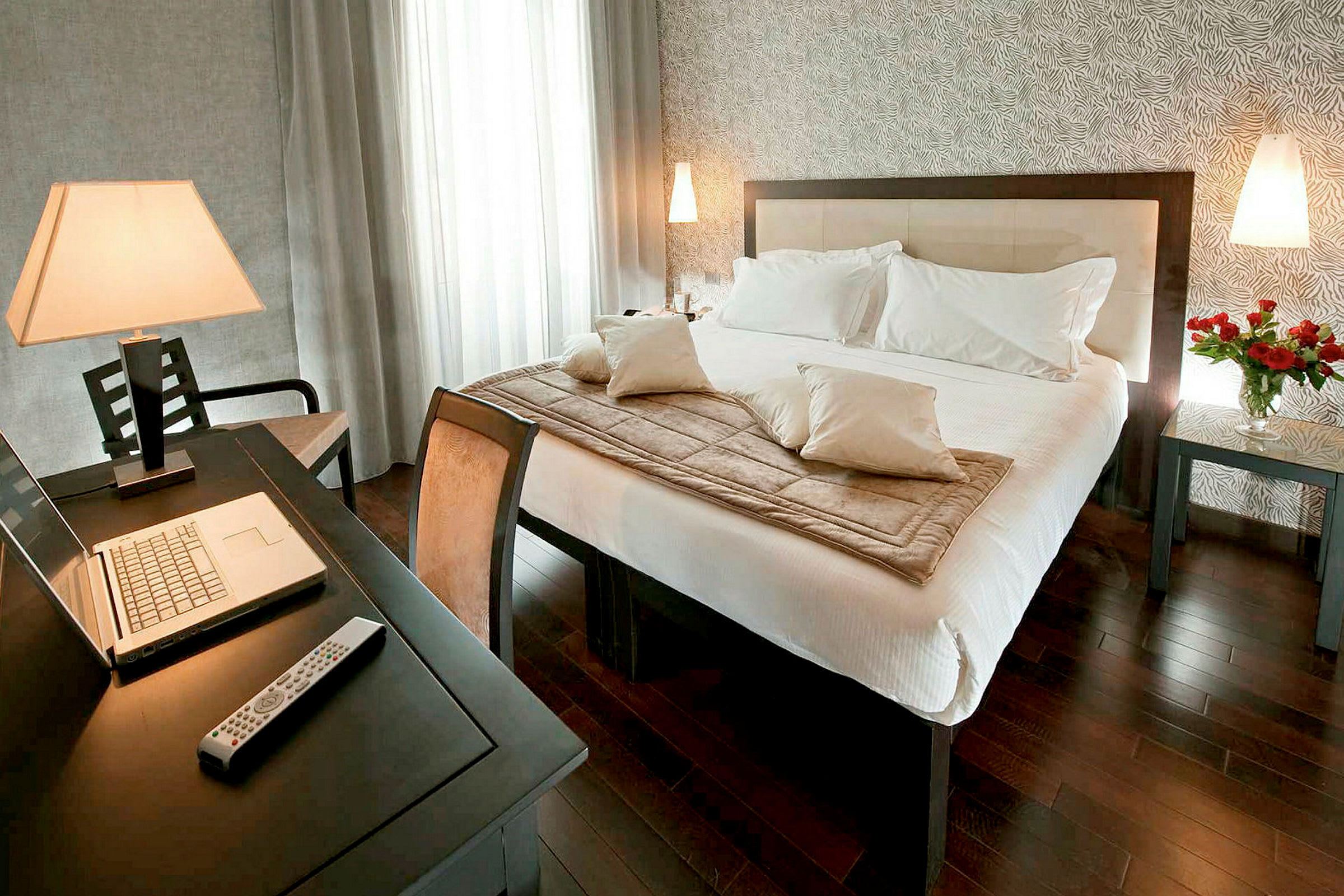 Bild på ett modernt hotellrum med en dubbelsäng, skrivbord och en laptop. (AI-genererad text)