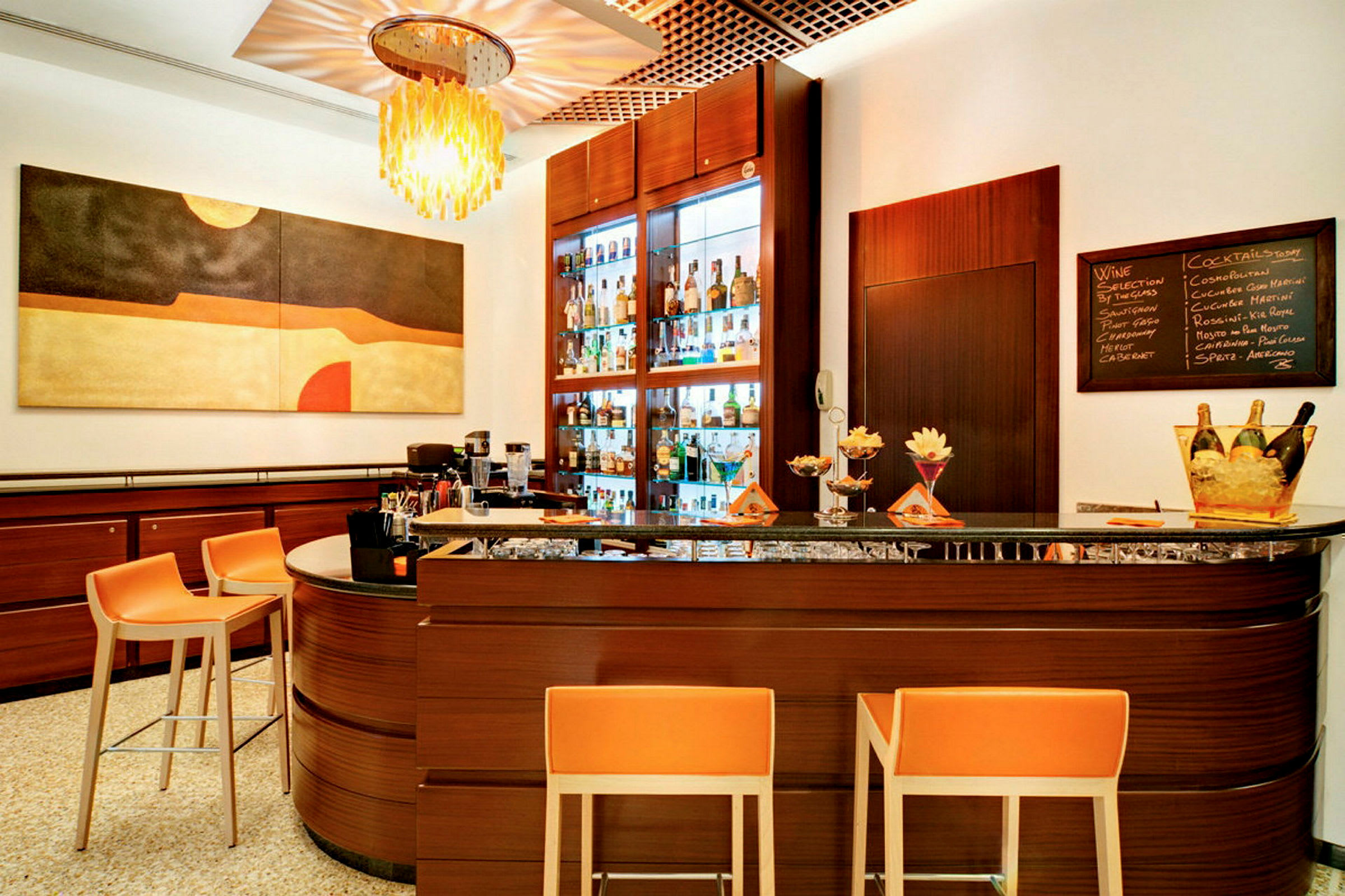 En modernt inredd hotellbar med orange stolar framför en mörkbrun bardisk. (AI-genererad text)