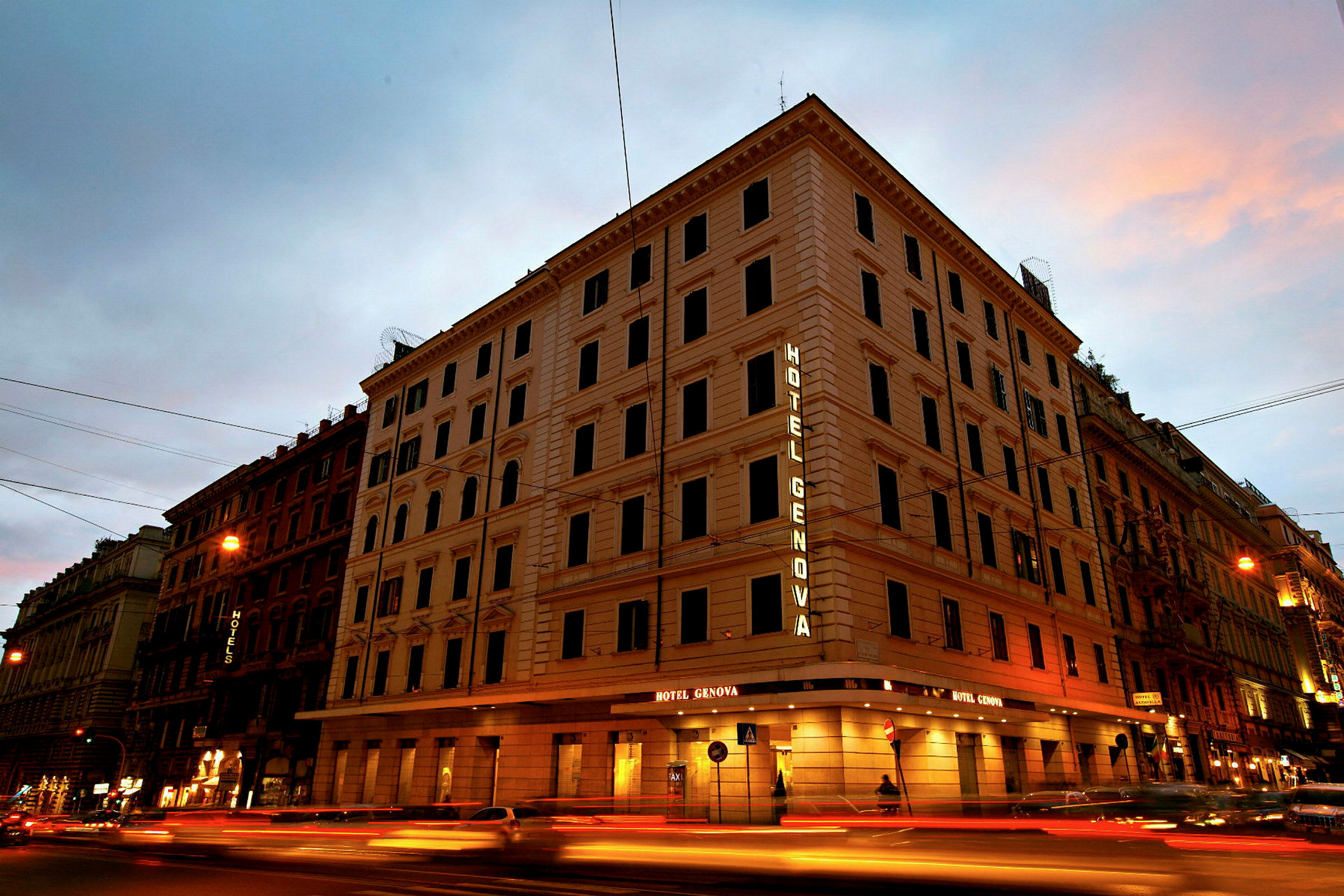 En fler vånings byggnad med texten Hotel Genova lysande på fasaden. (AI-genererad text)