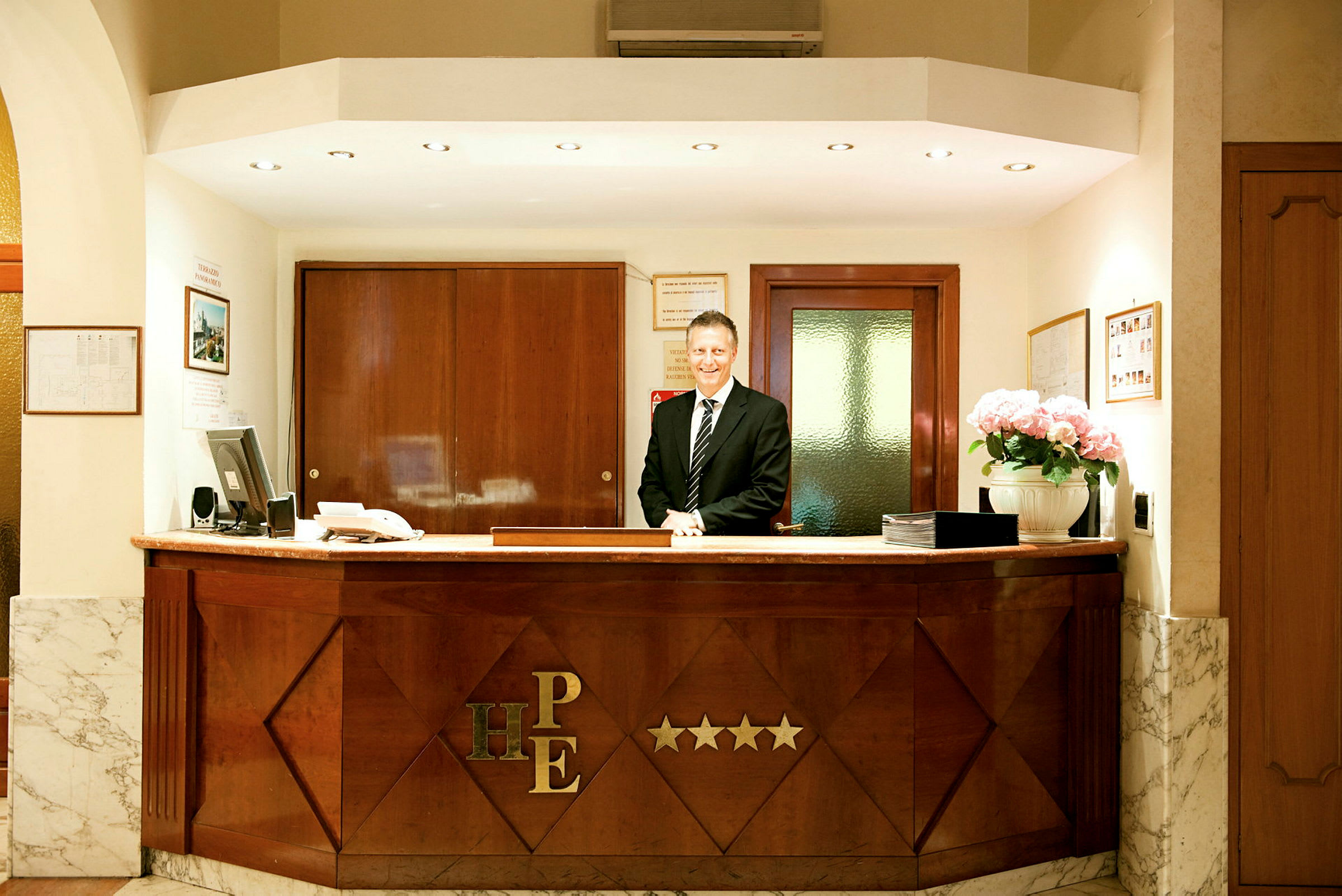 Receptionen på ett hotell med en desk och personal i kostym. (AI-genererad text)