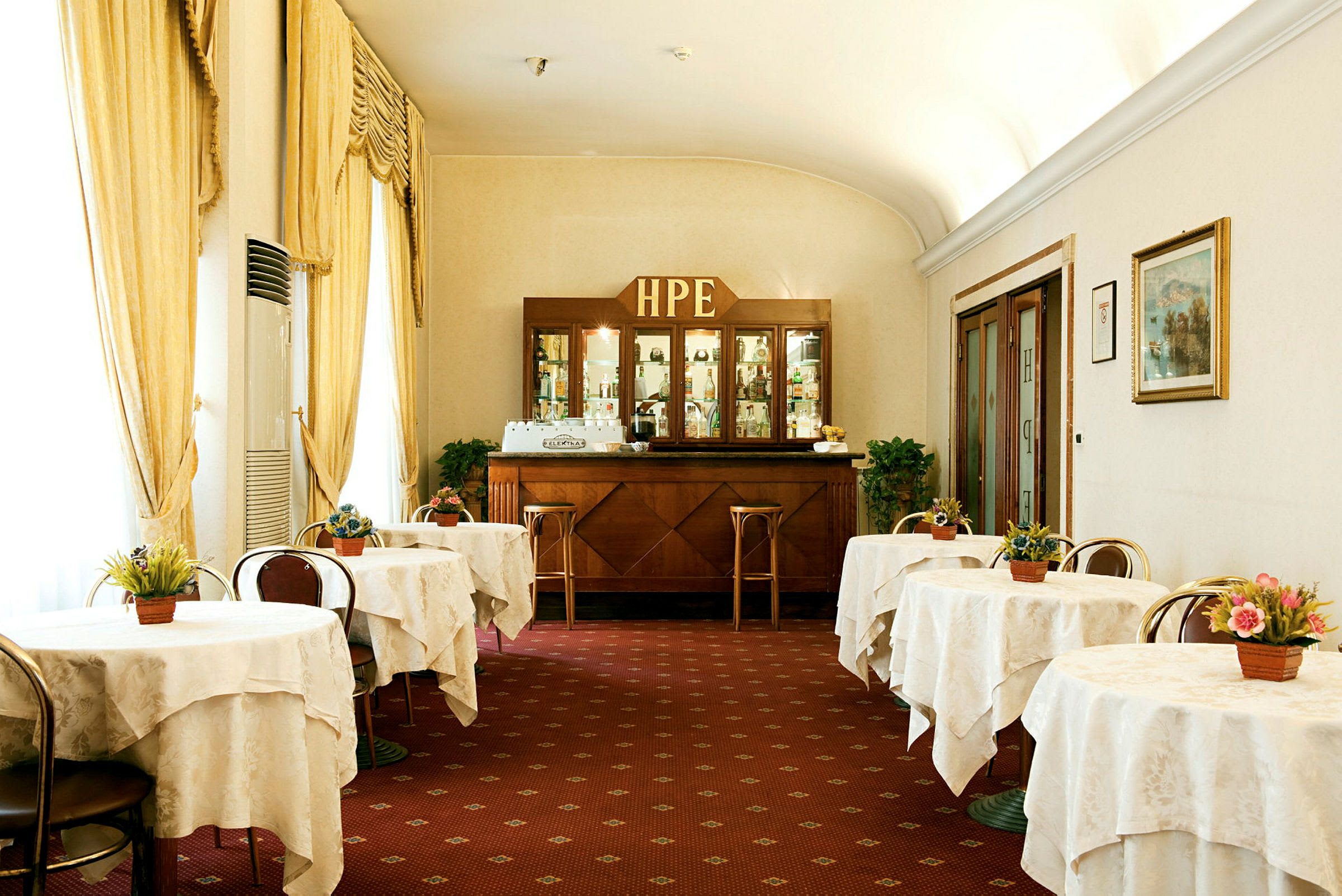Bild av en klassisk hotellcafémiljö med dukade bord och en träbar i bakgrunden. (AI-genererad text)