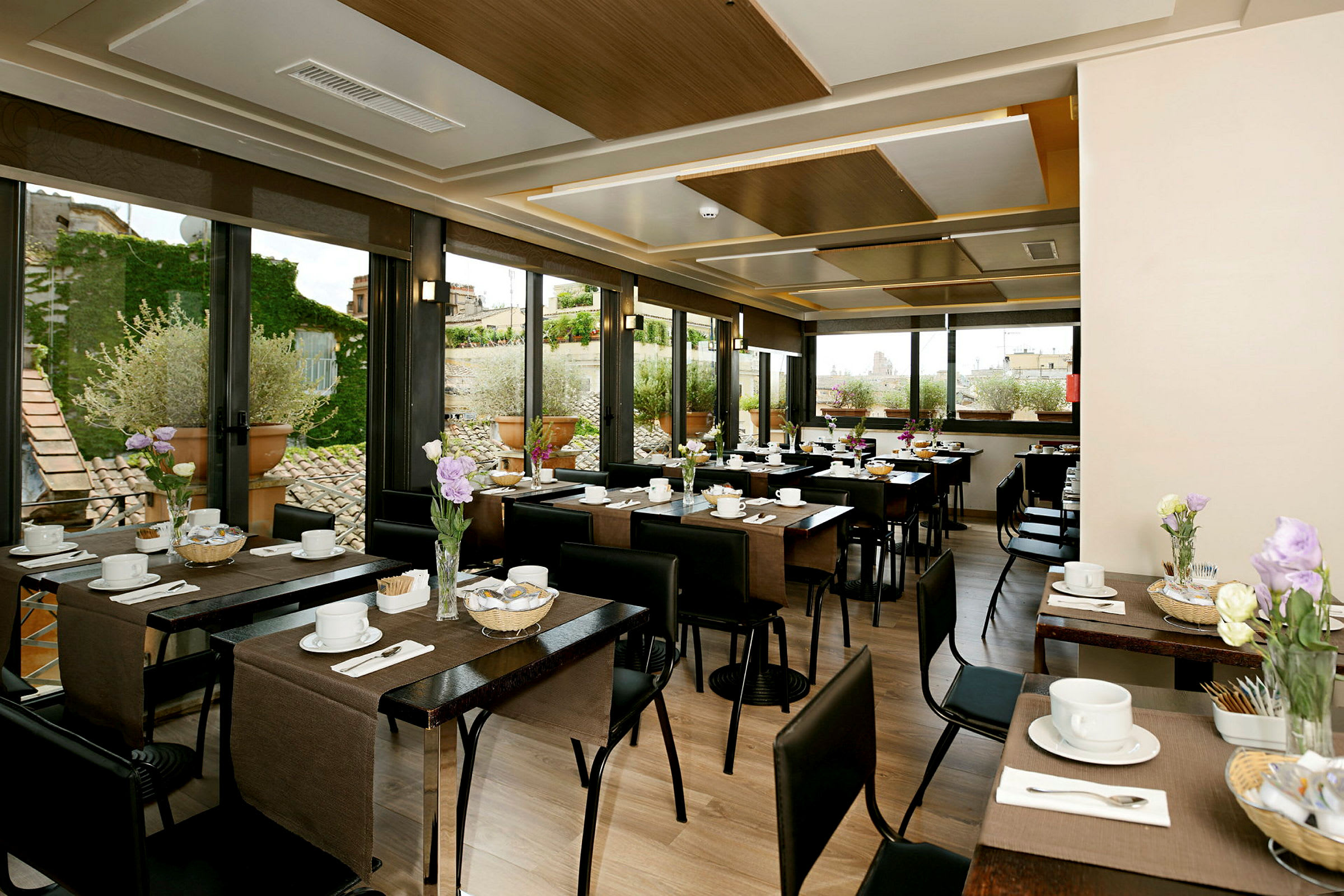 En ljus restaurang med dukade bord, dekorerade med blommor och fönster som visar en utomhusmiljö. (AI-genererad text)