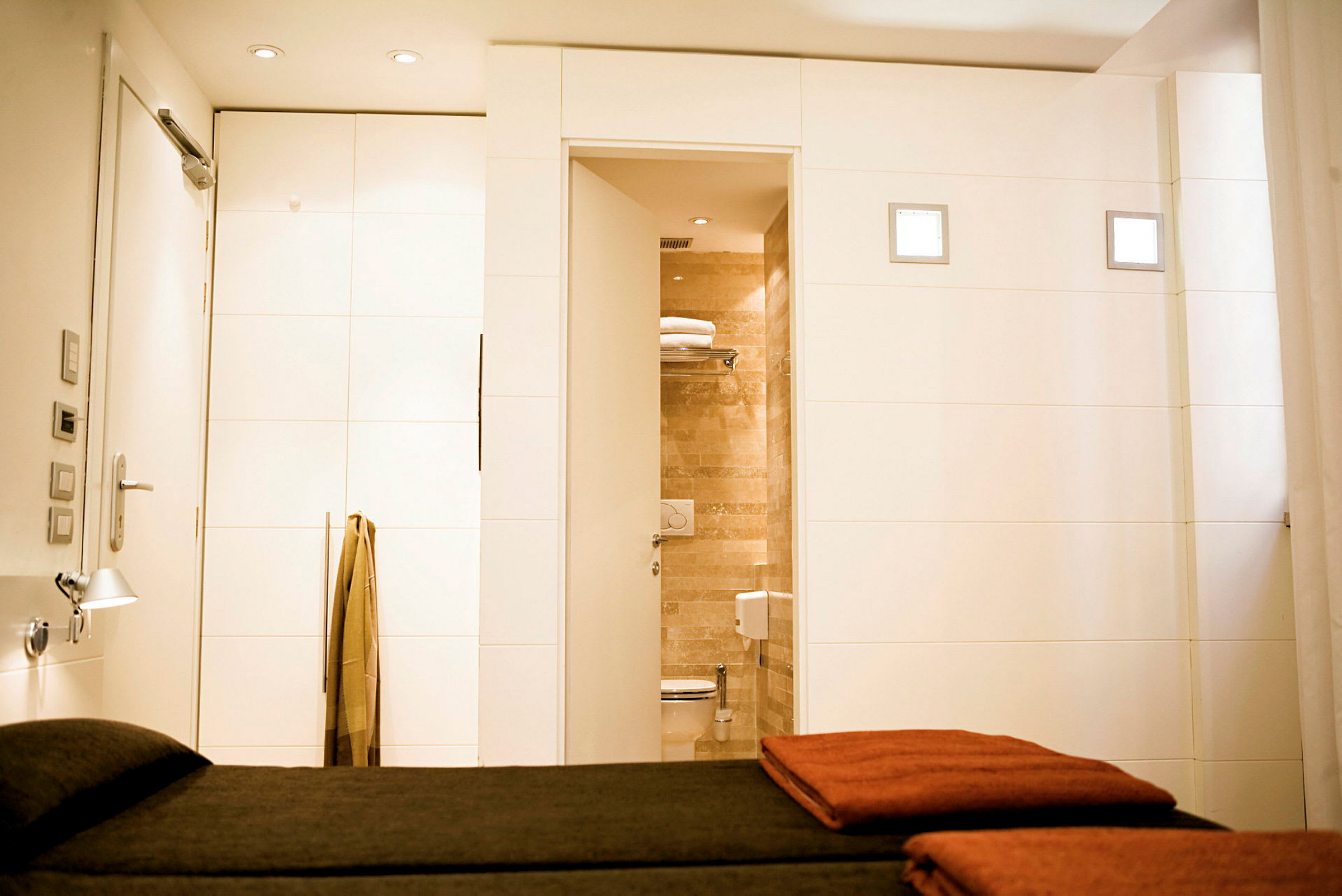 Interiör av ett hotellrum med säng i förgrunden och halvt öppen dörr till ett badrum. (AI-genererad text)