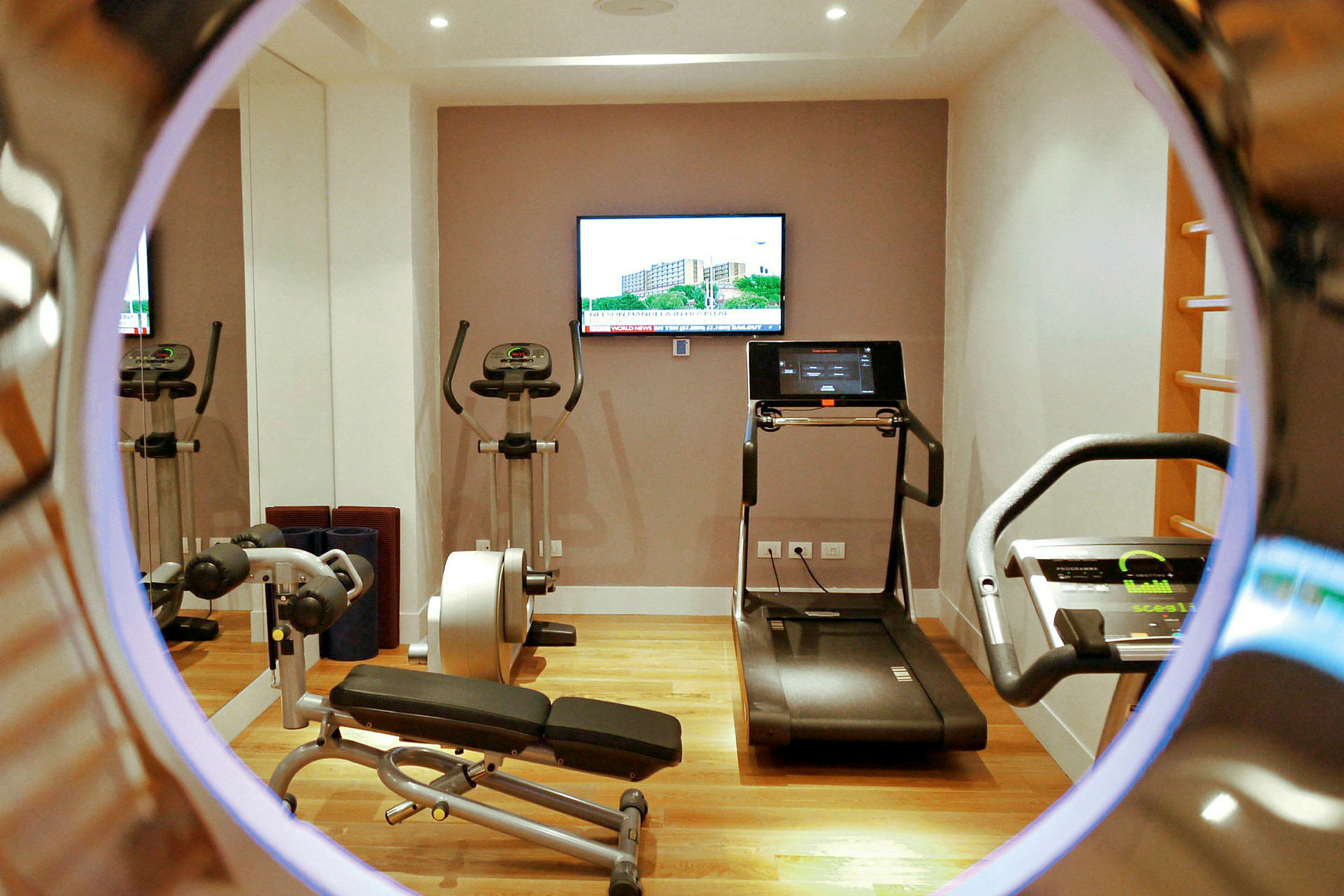 Ett gym med träningsmaskiner och en TV på väggen. (AI-genererad text)