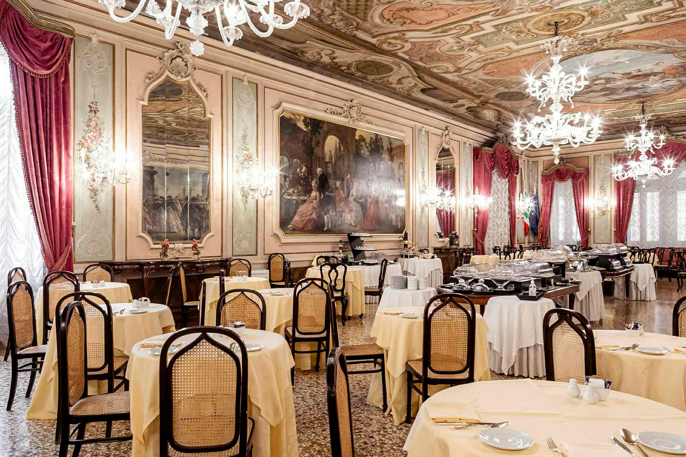 Rummet är en elegant matsal med dukade bord, kristallkronor och konstnärligt takmålning. (AI-genererad text)