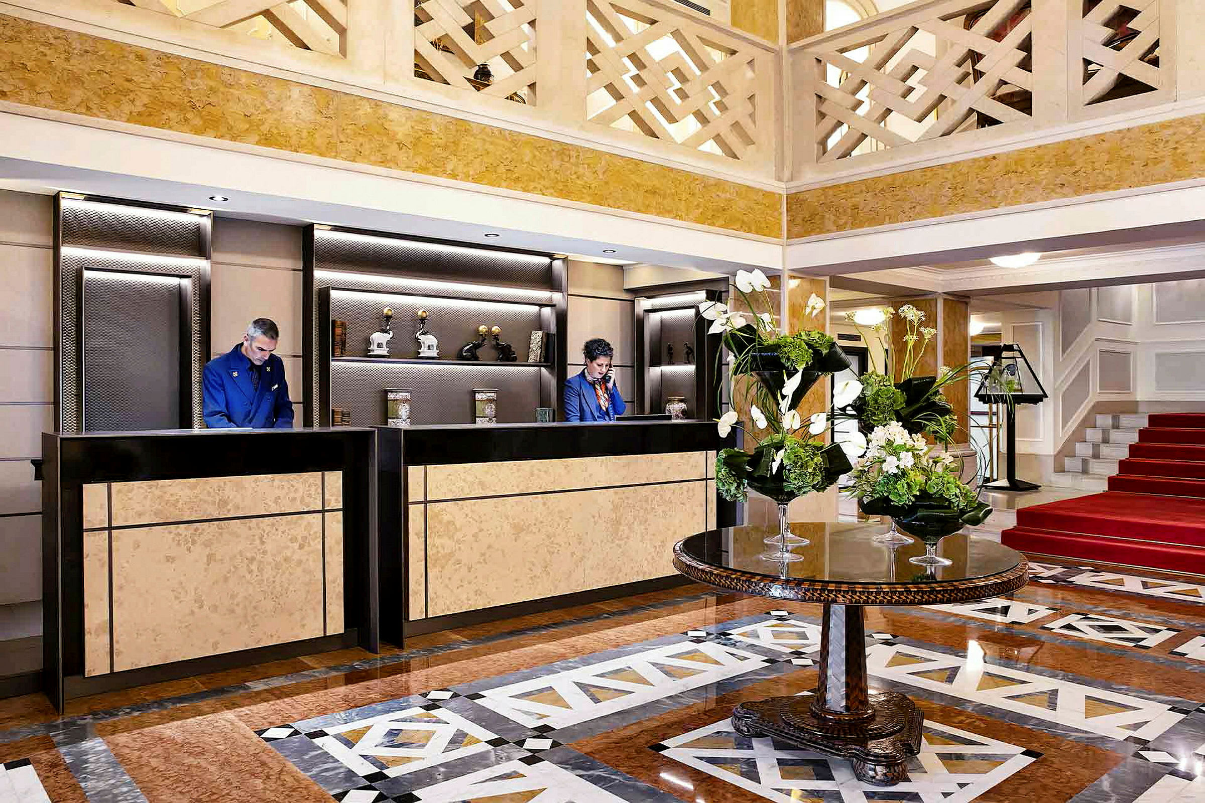 Interiör av en hotellobby med receptionsdiskar och ett bord med blomsterarrangemang. (AI-genererad text)
