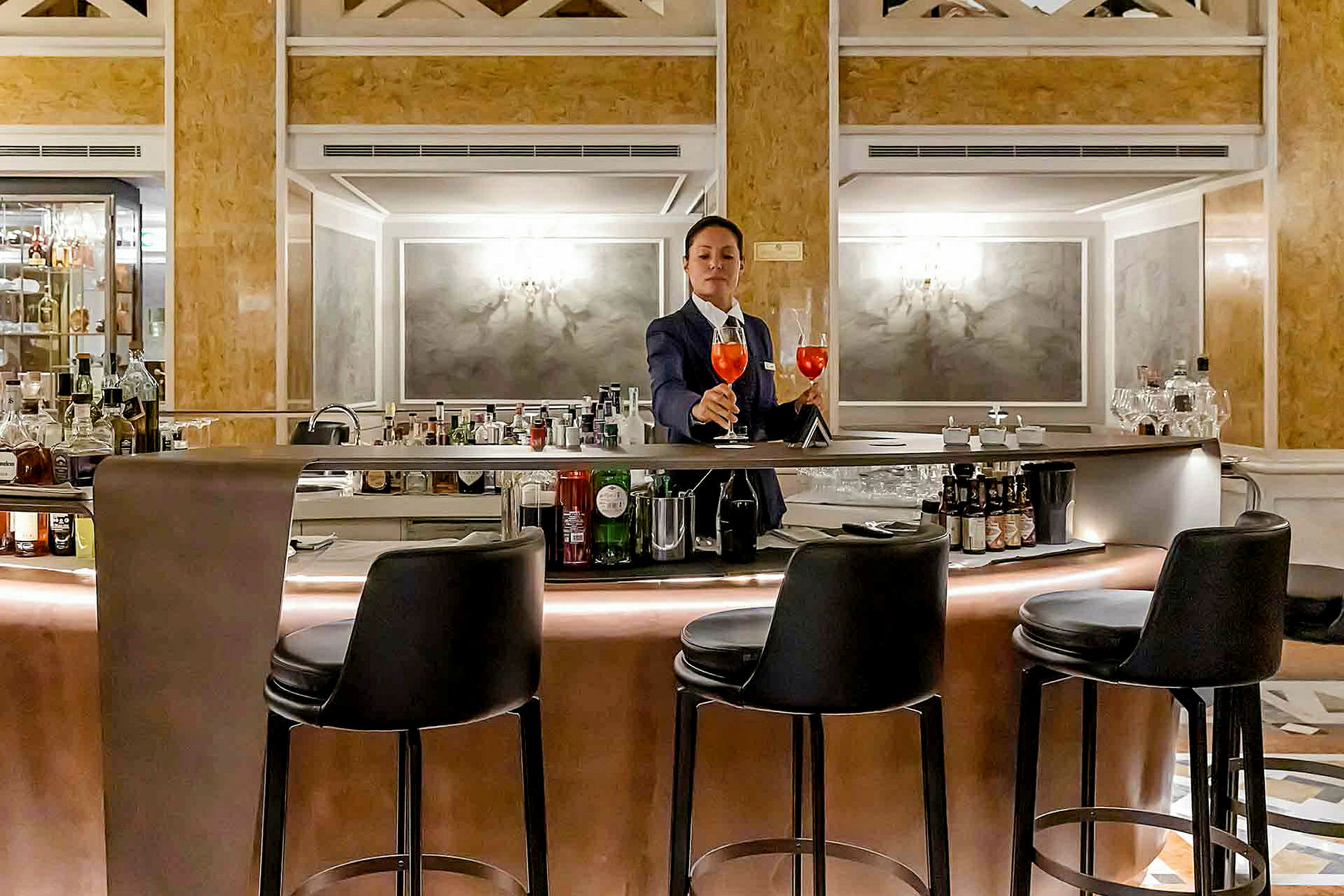 En bartender står vid en elegant bar med barstolar omkring. (AI-genererad text)