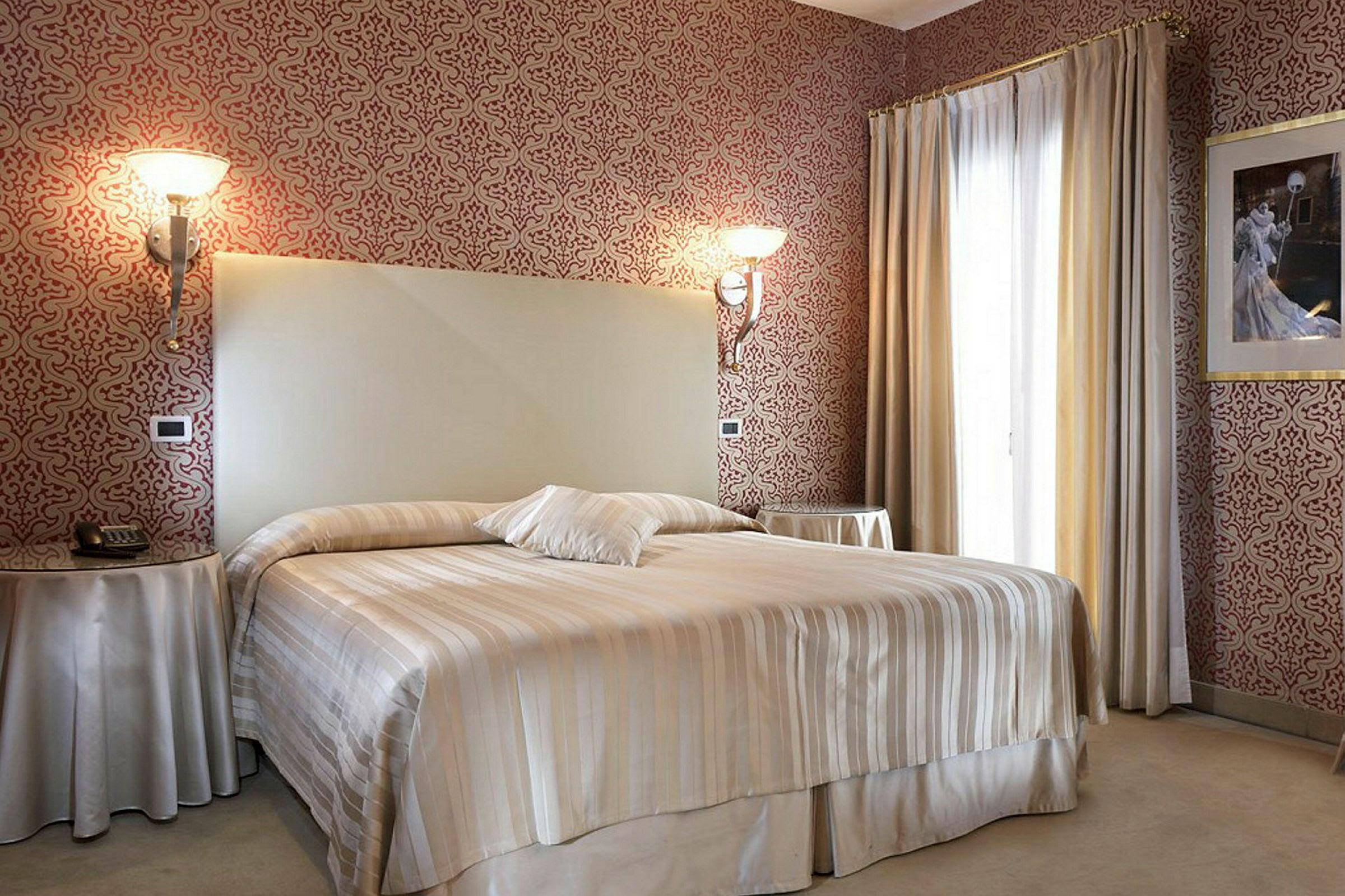 Ett hotellrum med en stor säng och dekorativa tapeter. (AI-genererad text)