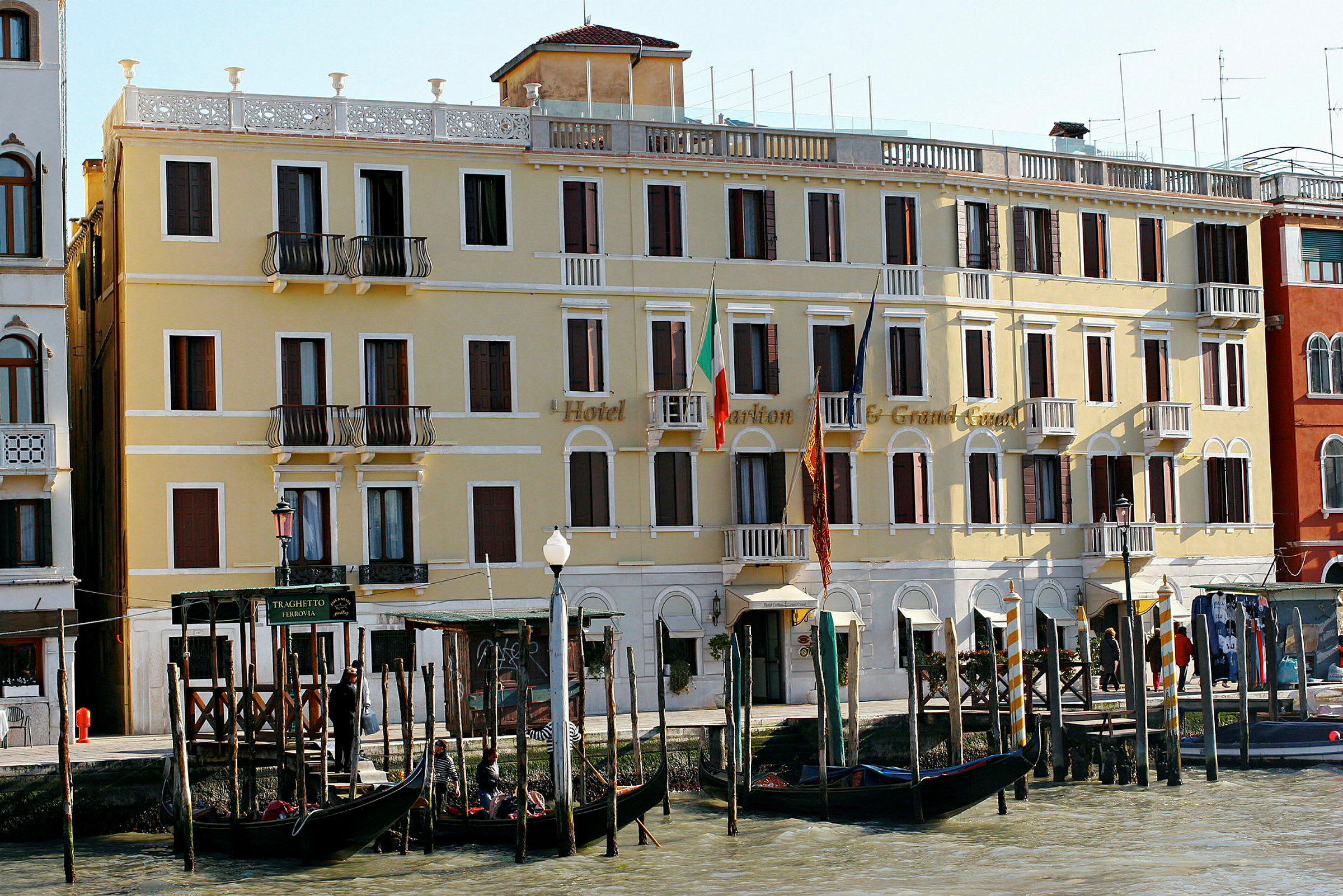 Ett gult hotell vid Grand Canal i Venedig med gondoler framför. (AI-genererad text)