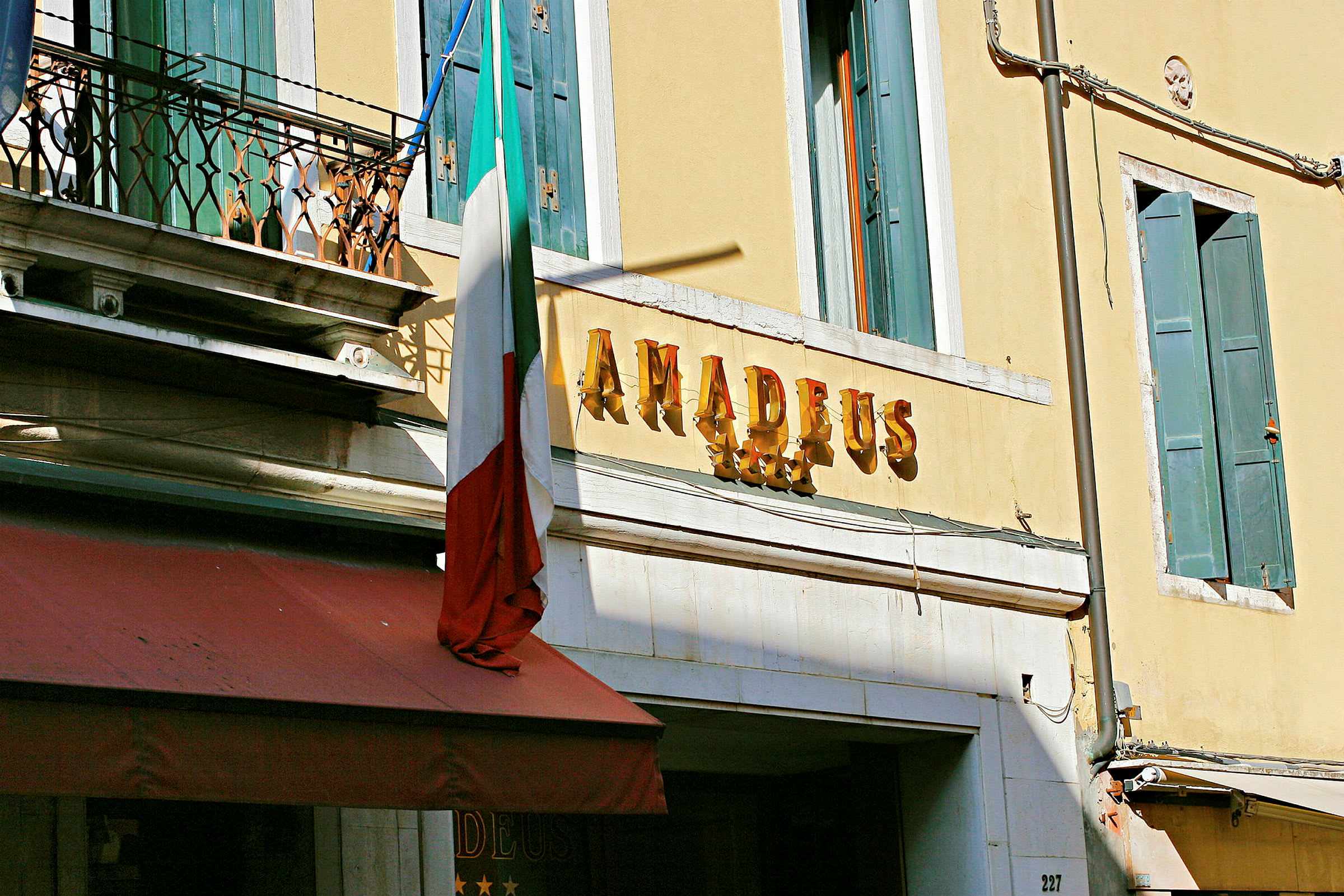 Hotellfasad med skylt som säger 'Amadeus' och en italiensk flagga. (AI-genererad text)