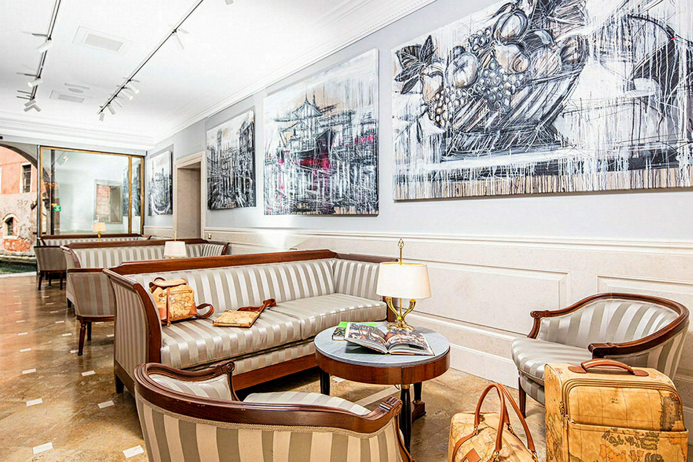 Ett elegant väntrum i en hotellobby med randiga soffor, ett bord med tidskrifter och lampor samt väggdekorationer. (AI-genererad text)