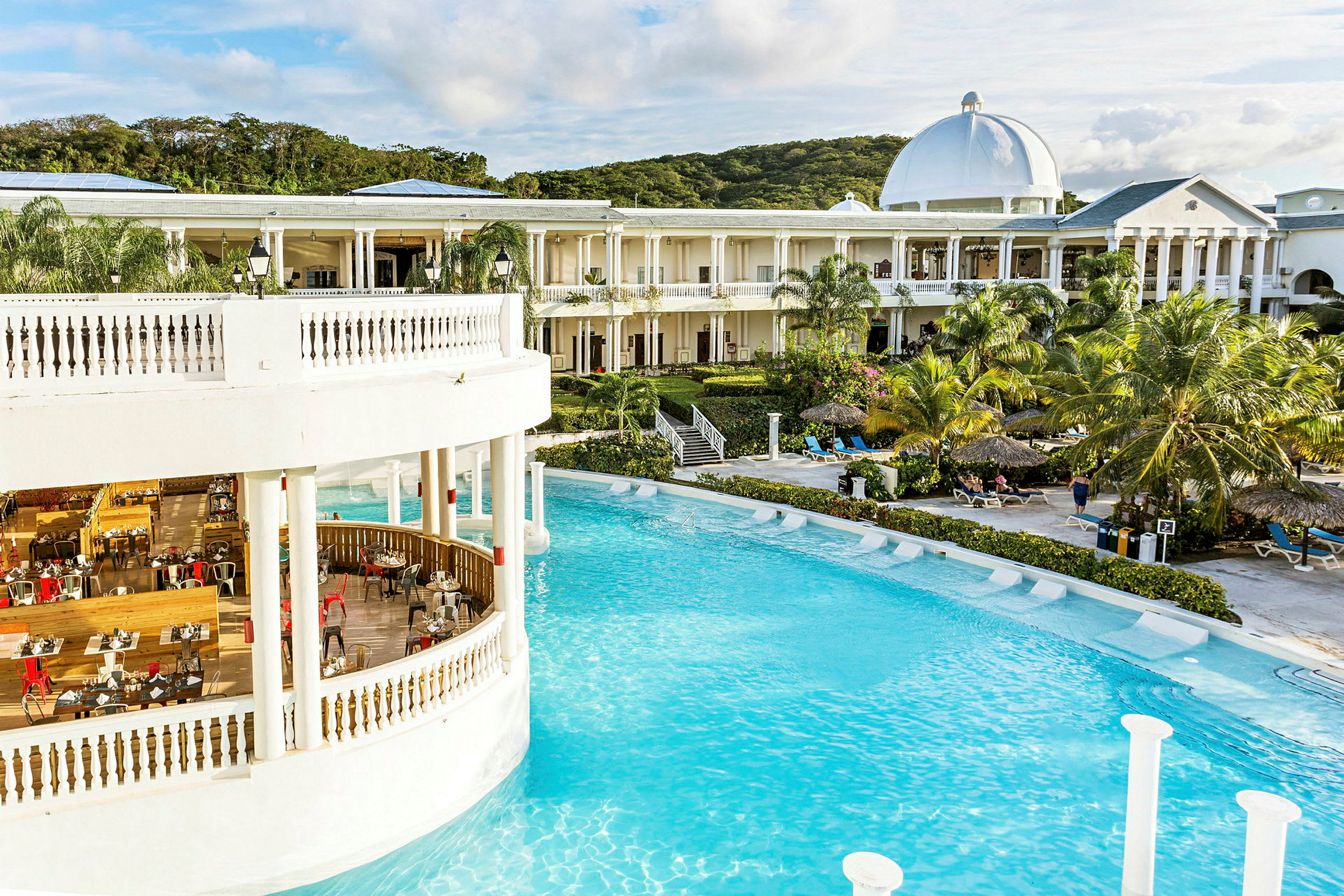Bild av hotell med pool, restaurang och omgivande trädgård. (AI-genererad text)