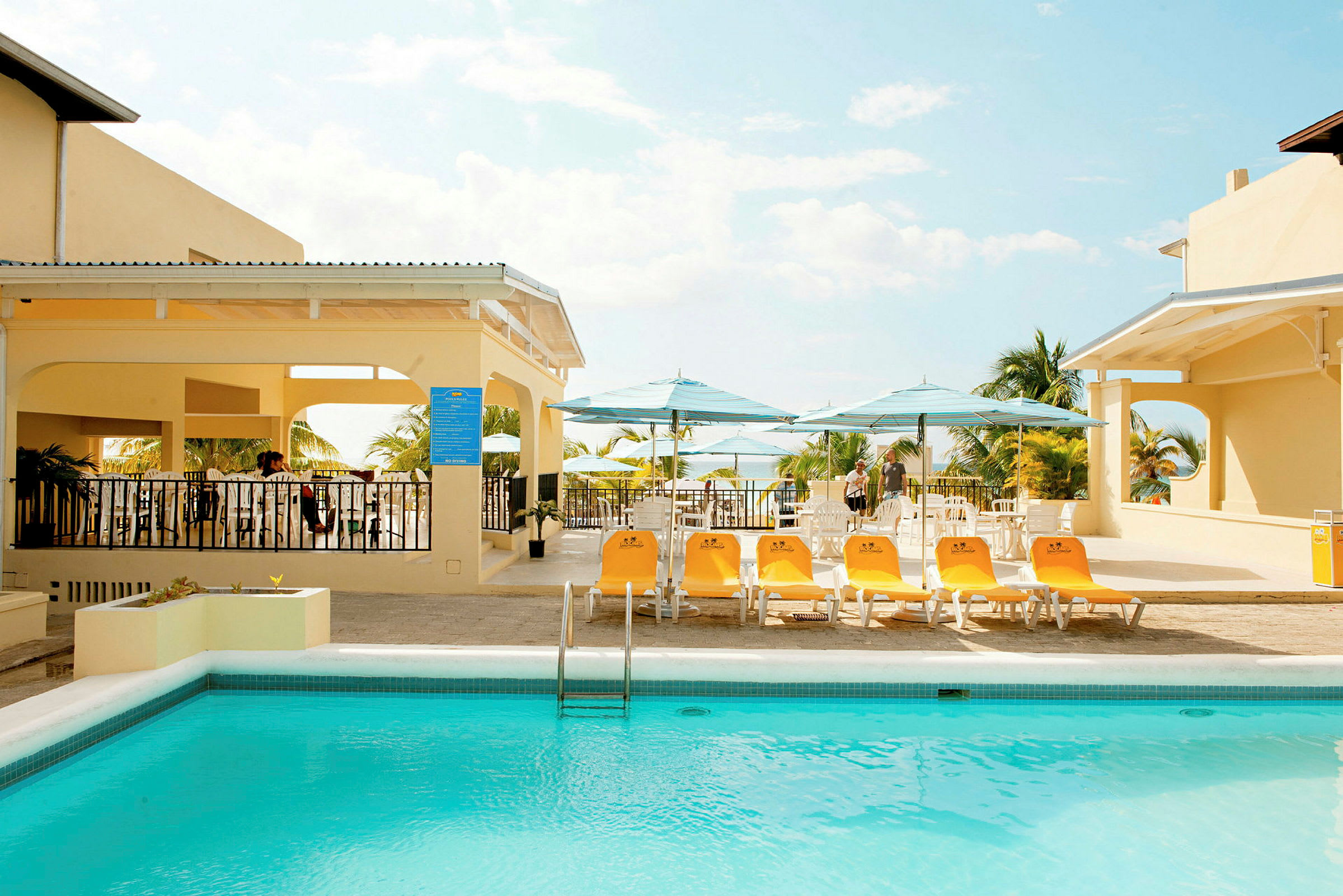 Utomhusområde med en pool, solstolar och parasoll vid en byggnad med veranda. (AI-genererad text)
