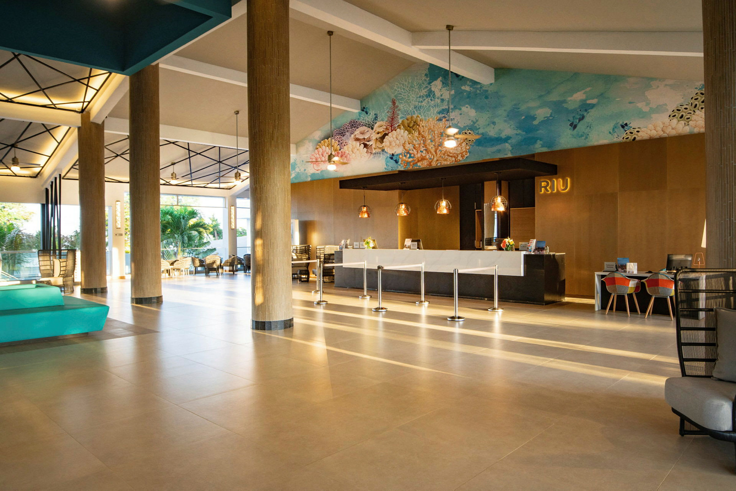 Bild av en hotellobby med ljusa golv, receptionsdisk, sittplatser och konstverk på väggen. (AI-genererad text)