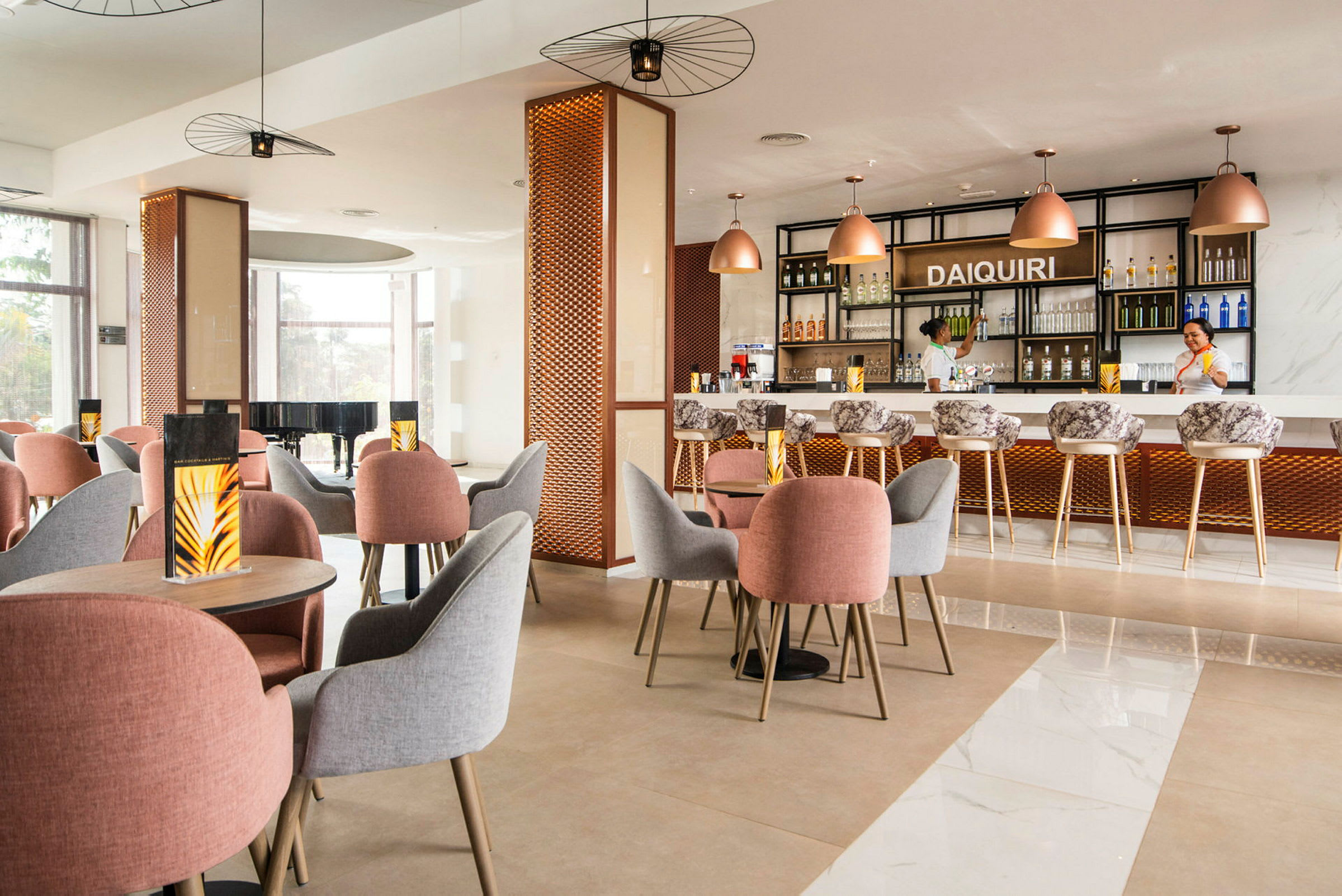 Ett modernt inrett café eller bar med bord och stolar av olika färger samt en upplyst bardisk i bakgrunden. (AI-genererad text)