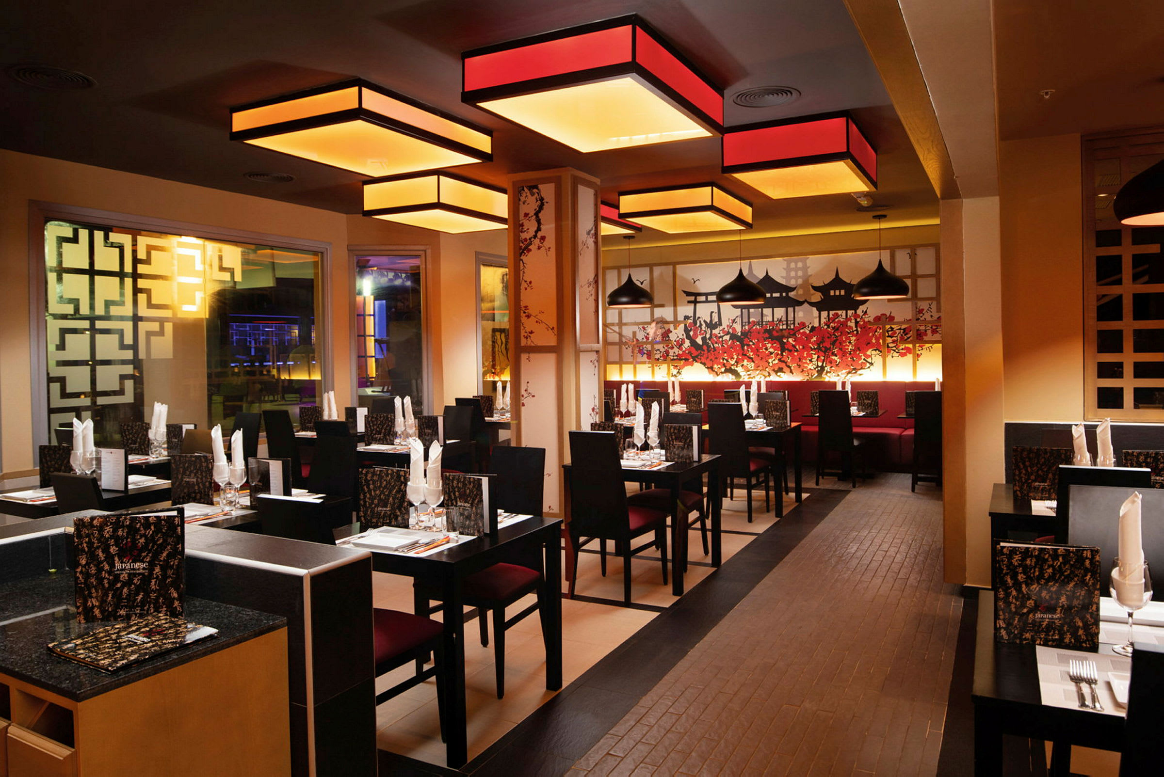 En stilfull restaurang med asiatiskt inspirerad inredning och bord uppdukade med servetter och glas. (AI-genererad text)