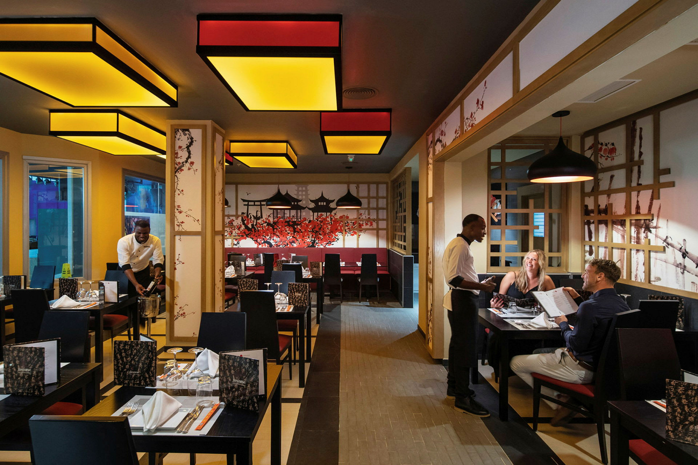 En restaurang med dekorationer inspirerade av asiatisk kultur och personal som betjänar gäster. (AI-genererad text)