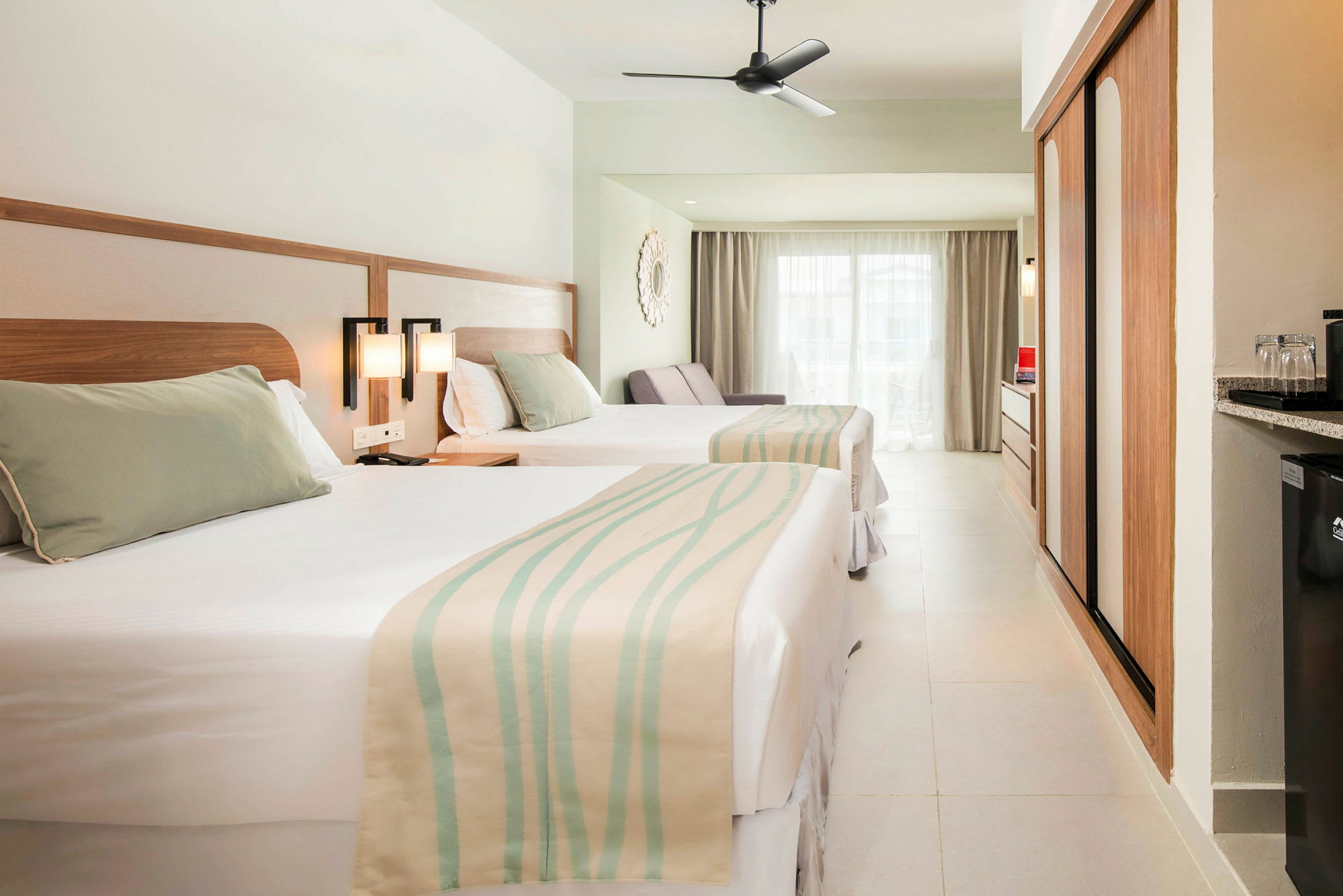 Hotellrum med två sängar, ljus inredning och stora fönster. (AI-genererad text)