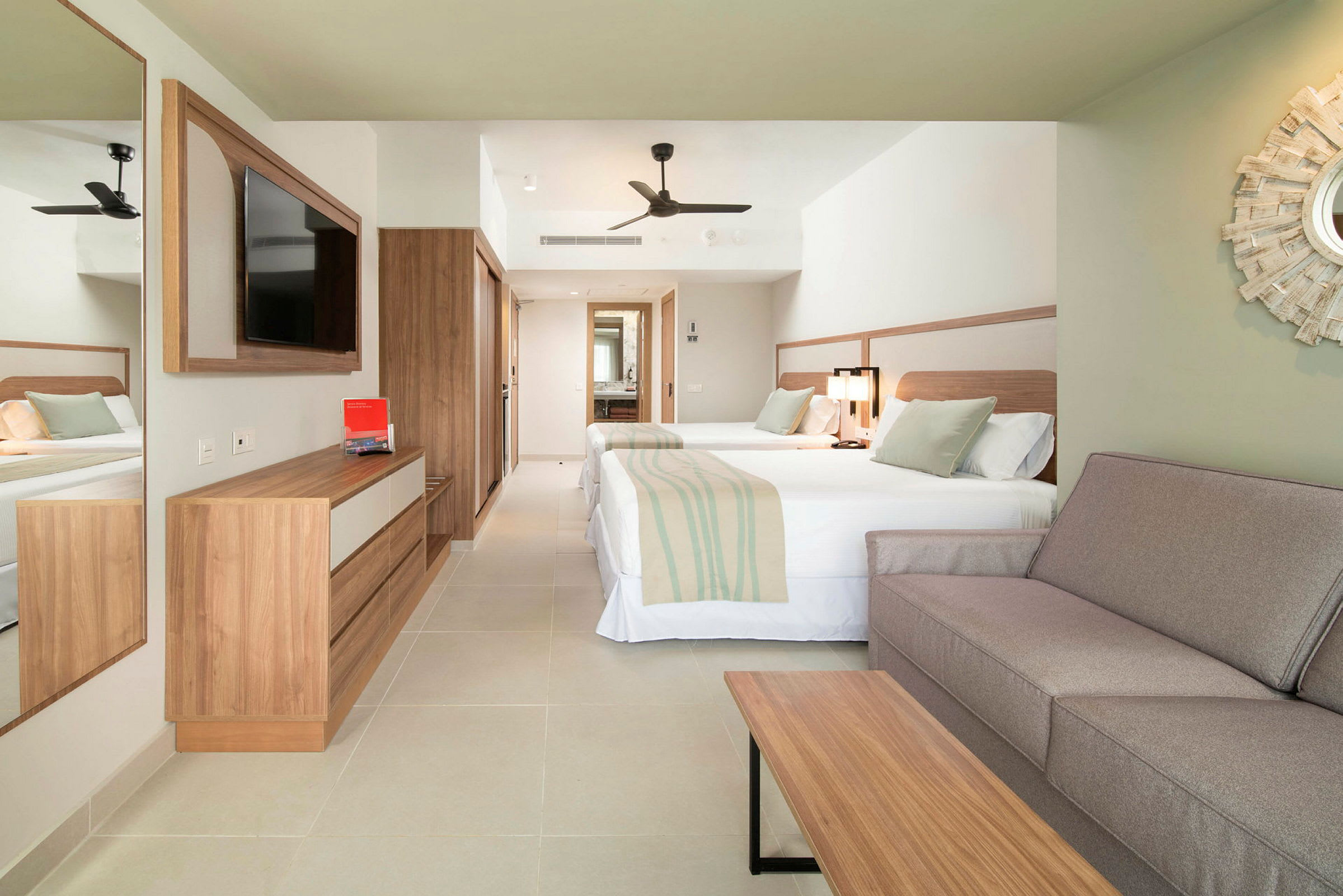 Hotellrum med två sängar, en soffa och en TV. (AI-genererad text)