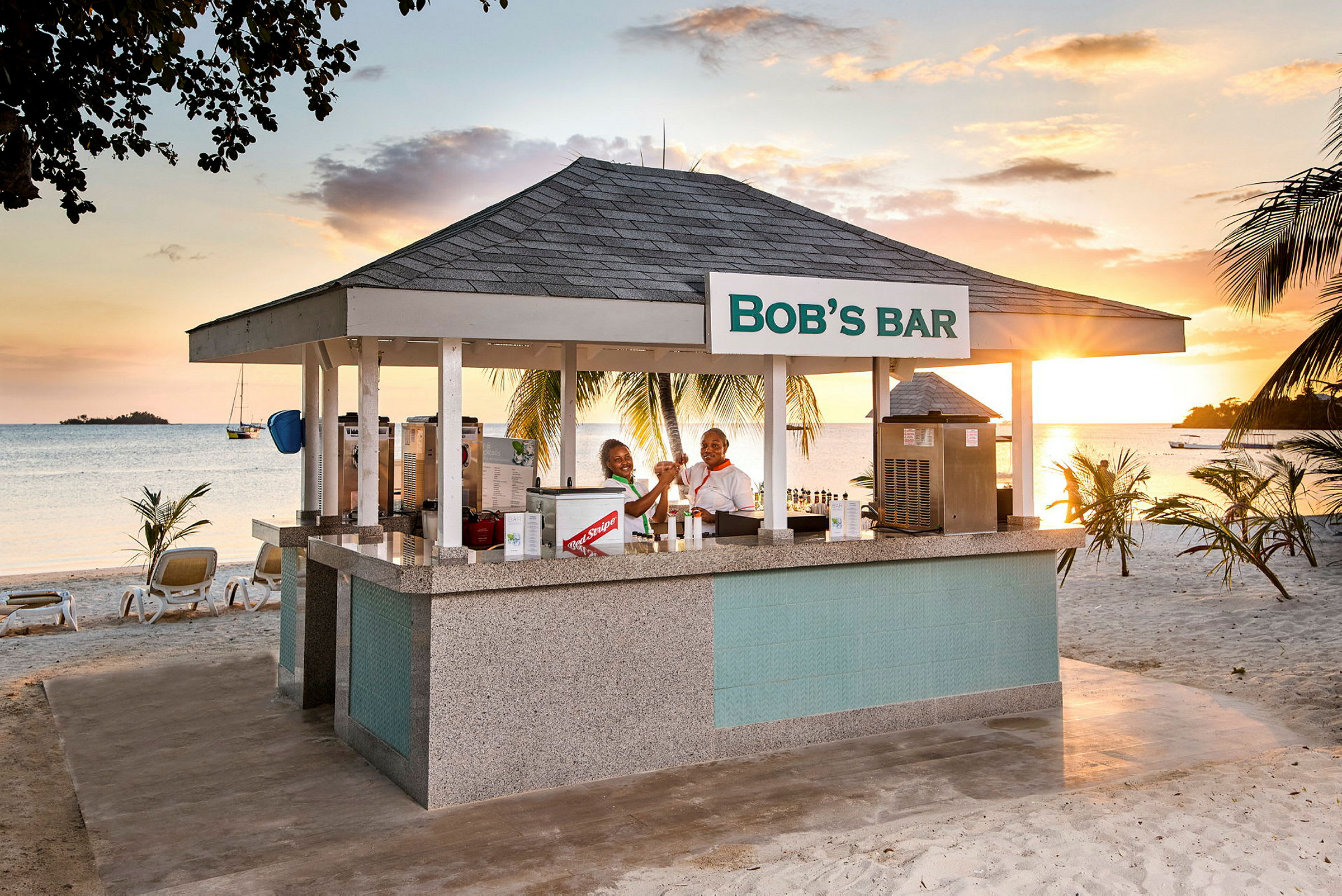 Strandbar med tak och skylt som lyder 'Bob's Bar', omgiven av palmer och med havsutsikt. (AI-genererad text)