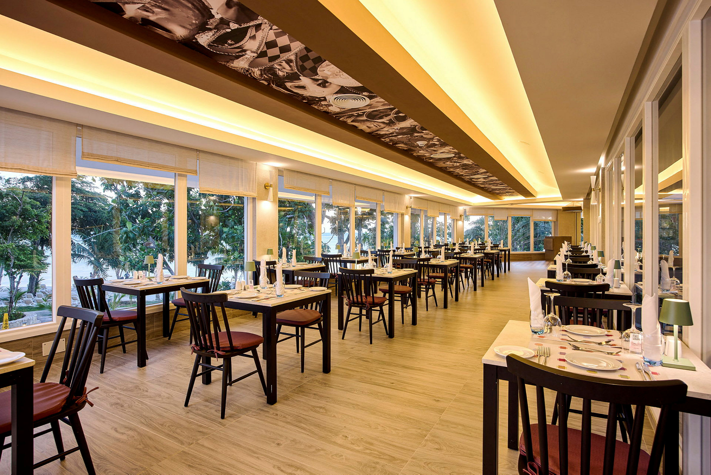 Interiör av en restaurang med dukade bord och stora fönster. (AI-genererad text)