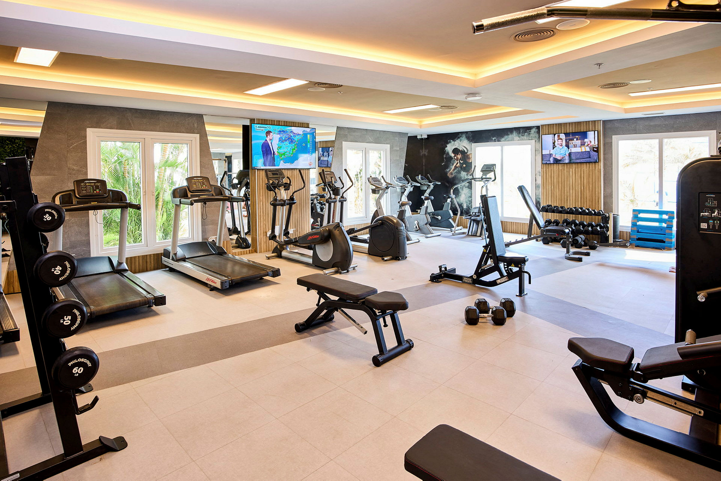 Bild av ett gym med träningsutrustning som löpband, motionscyklar och vikter. (AI-genererad text)