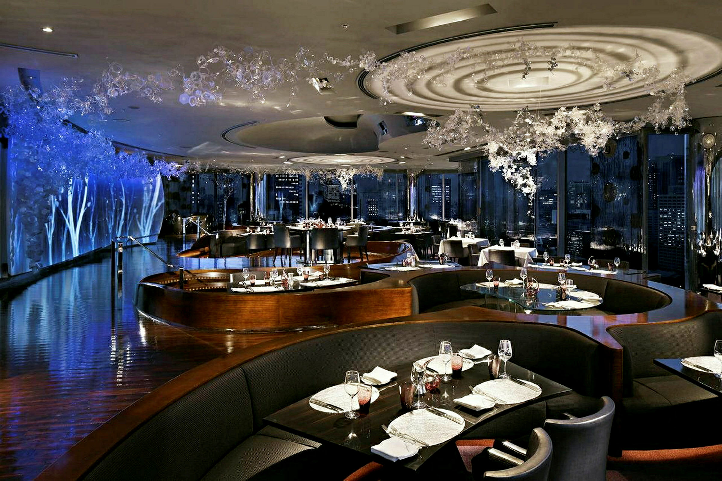 En elegant restaurang med stilfull inredning, där borden är prydligt dukade och omgivna av mörka sittplatser. (AI-genererad text)